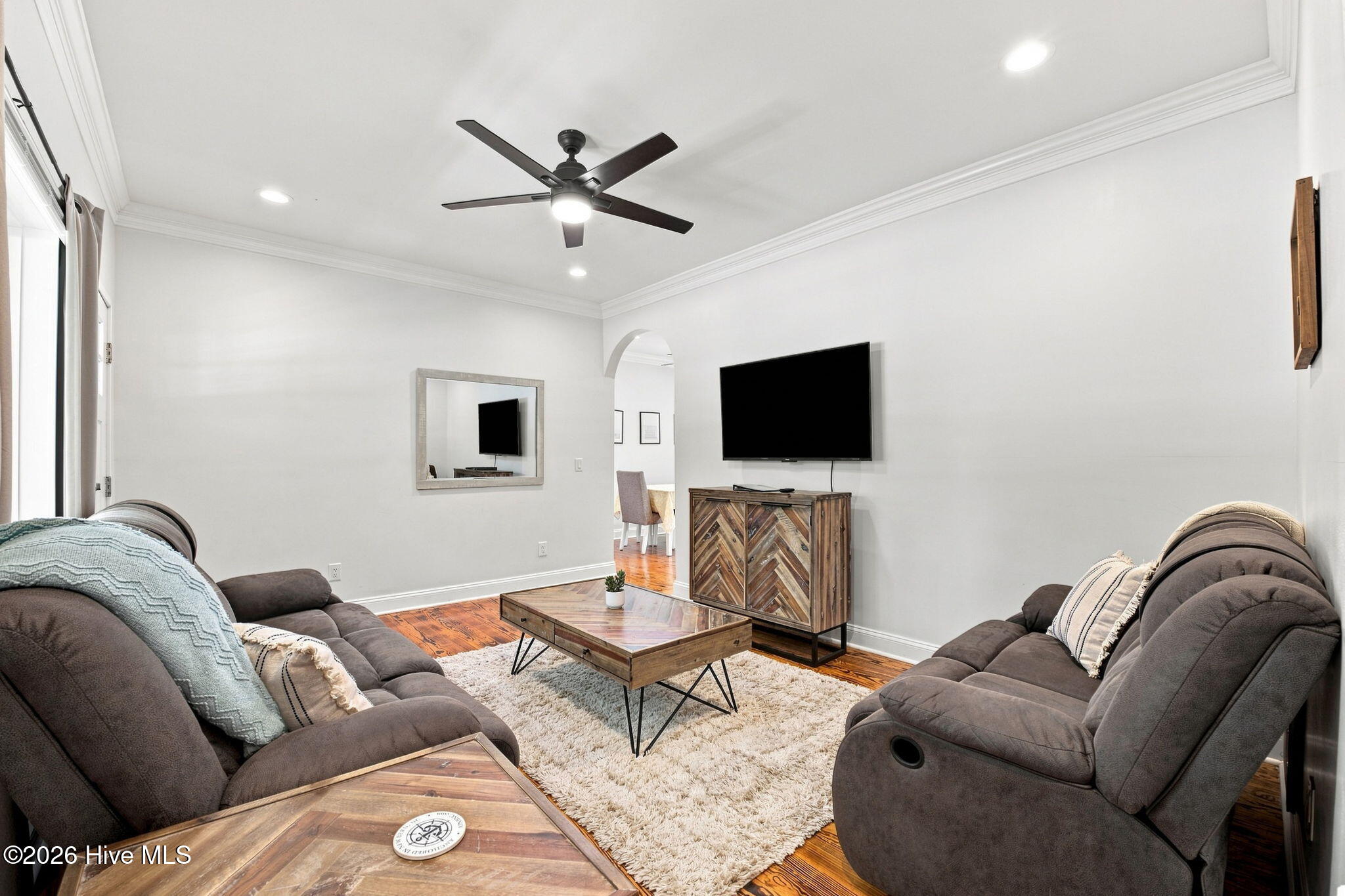 Furnished living room with gray sofas, a white shag rug, and a wall-mounted television.