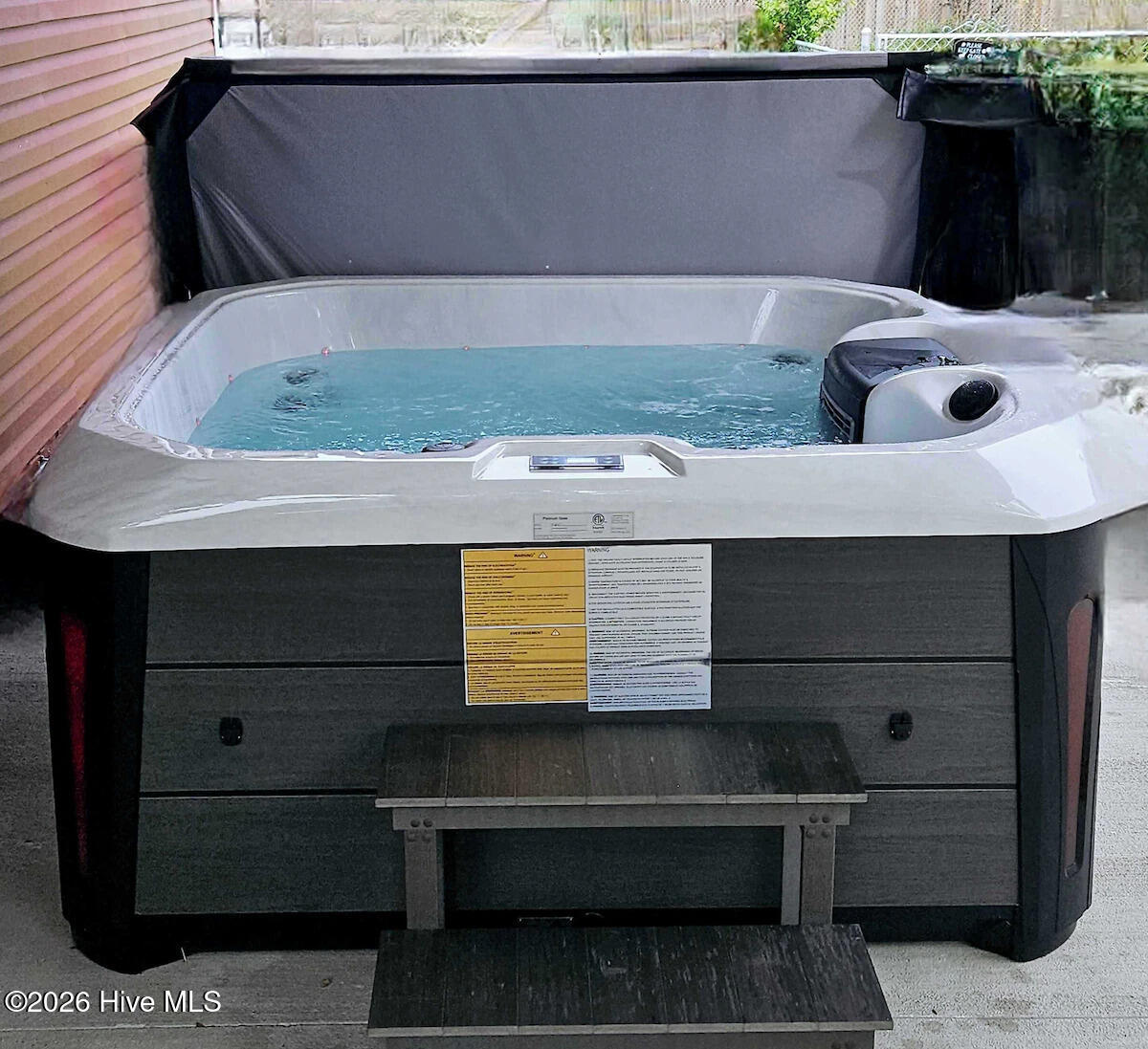 Outdoor hot tub with its cover open beside the house.