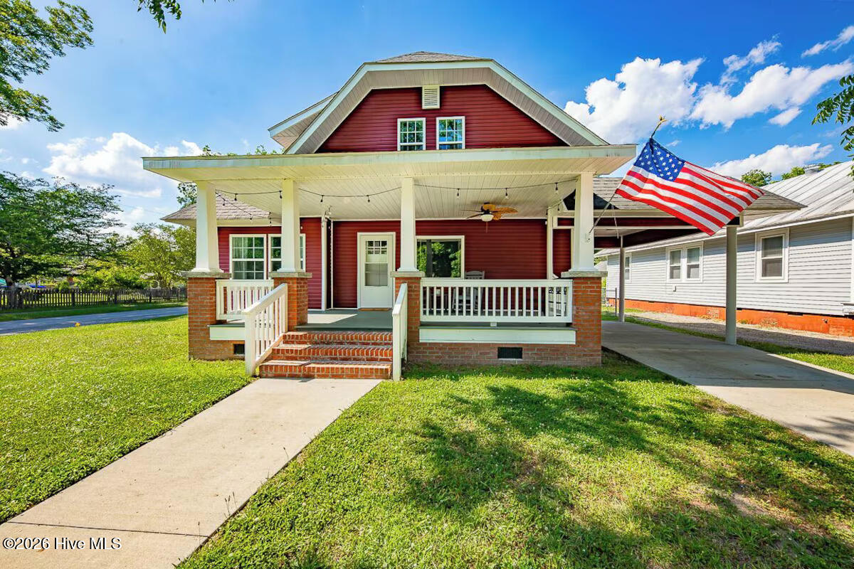 Red two-story house with a broad white-columned porch and an American flag.