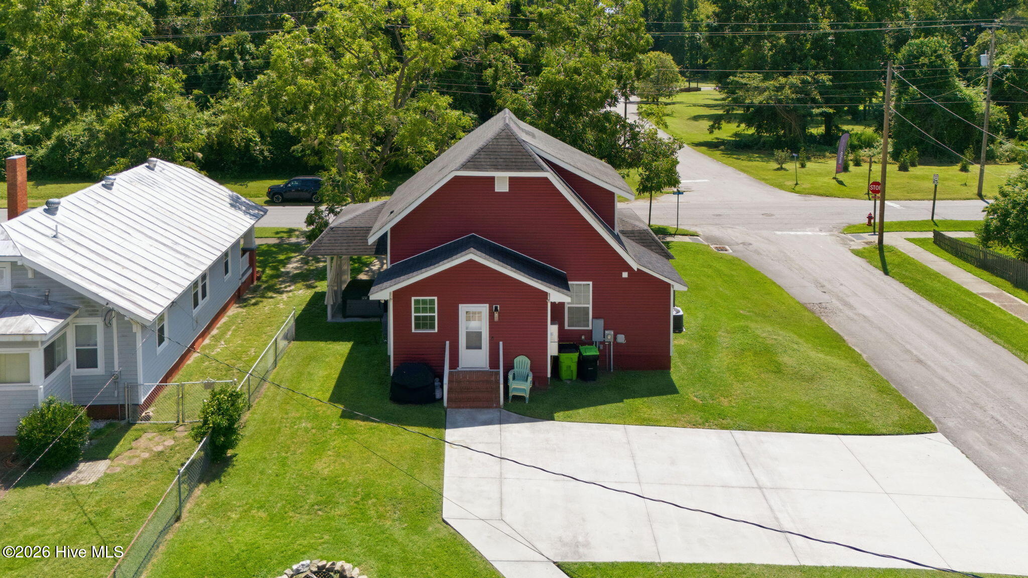 Red house viewed from above, showing its rear entrance, steep roof, and broad concrete driveway.