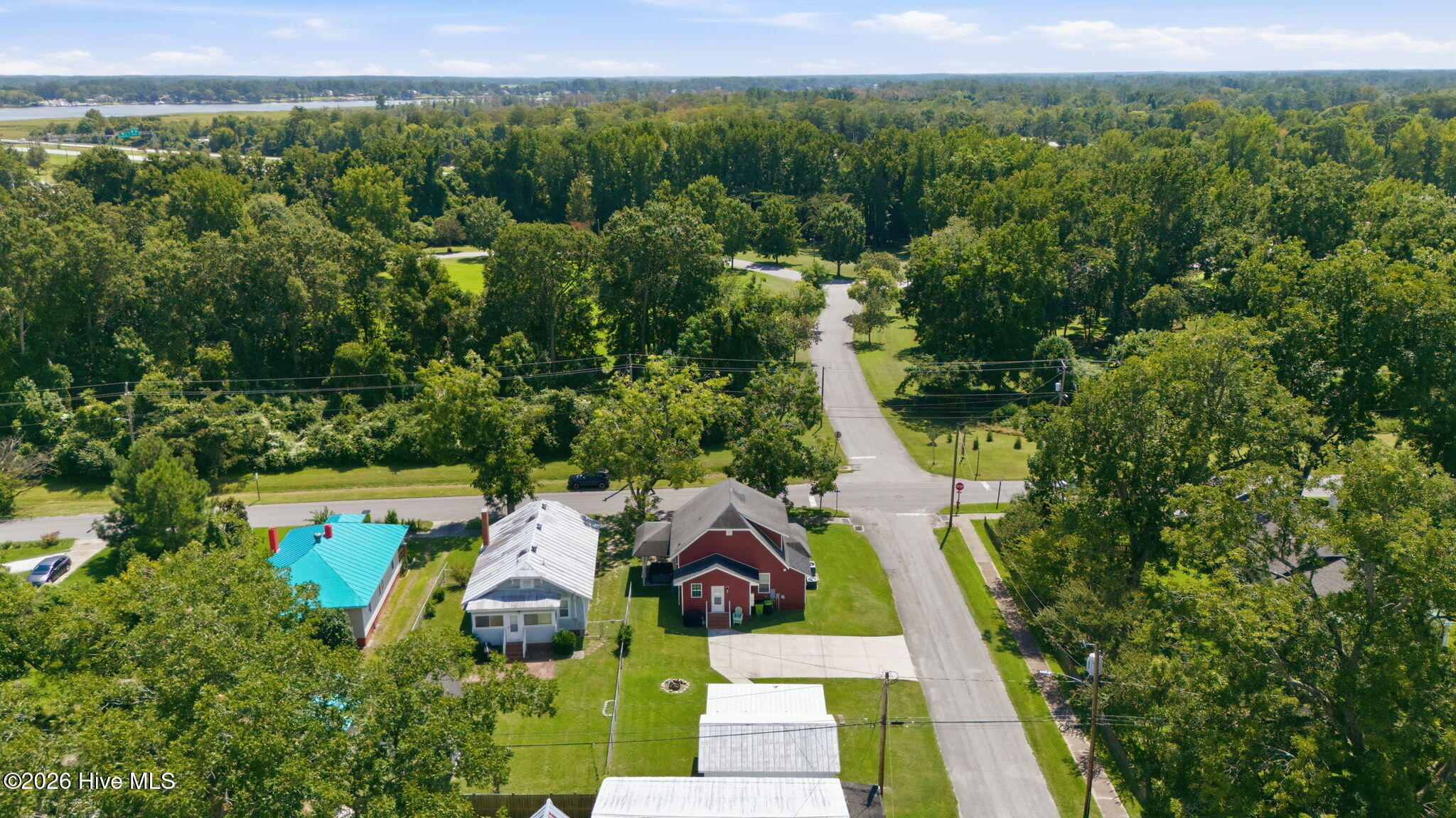 Aerial view of 1422 Park Avenue, with the red house beside a tree-lined street and distant water.