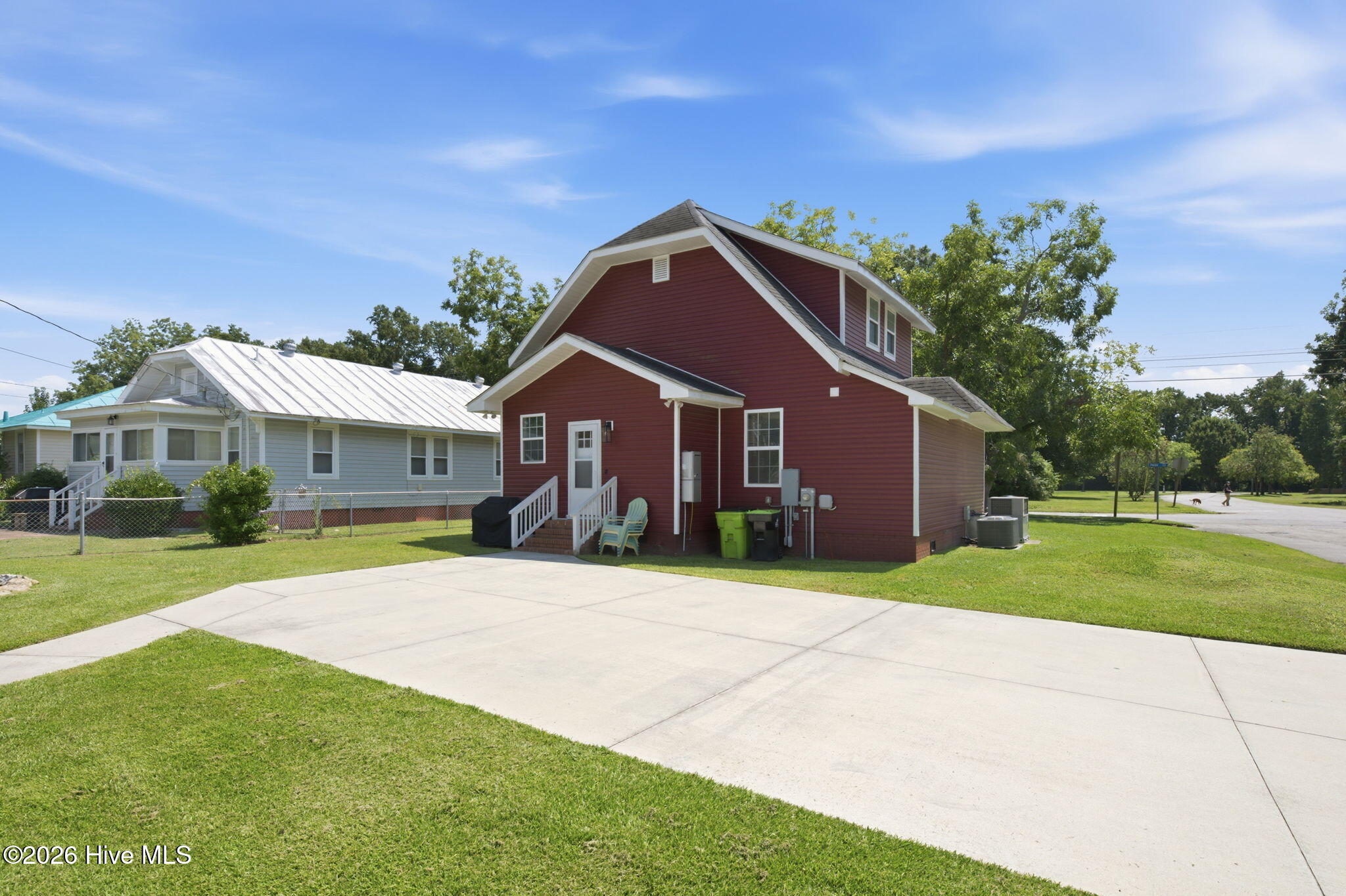 Burgundy two-story house with white trim, a small porch, and a wide concrete driveway.
