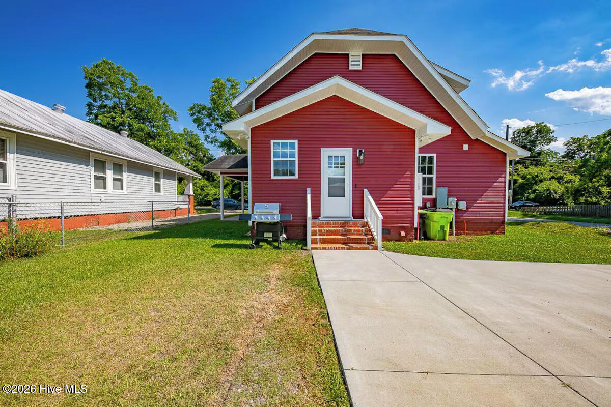 Red-sided house with white trim, brick entrance steps, and a wide concrete driveway.