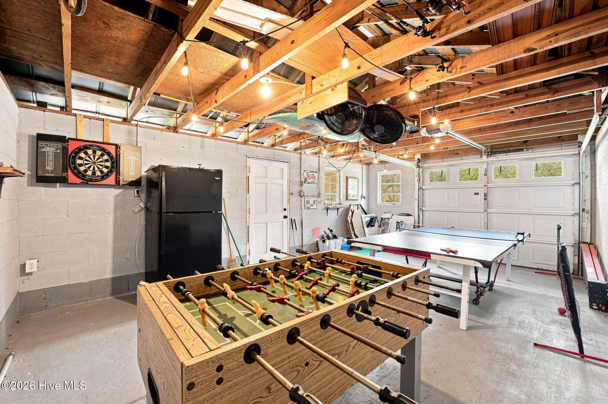 Garage game room with foosball and ping-pong tables beneath exposed timber beams.