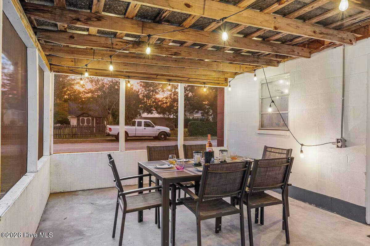 Covered patio with a dining set, exposed wood ceiling, and open window bays overlooking the street.
