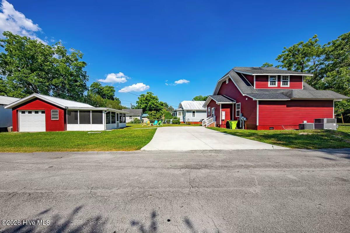 Red house with detached garage and wide concrete driveway.