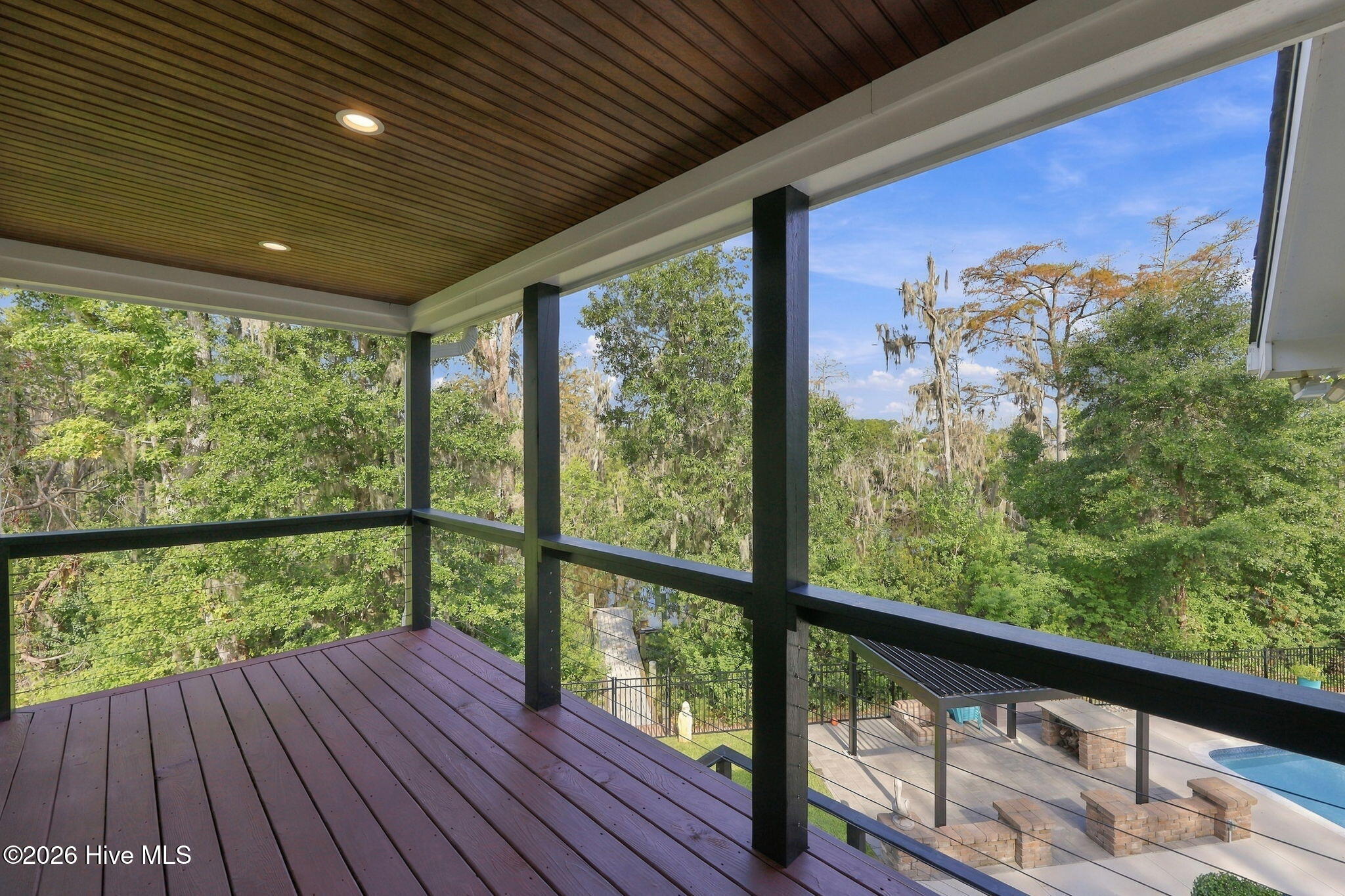 Covered deck overlooking leafy trees and a backyard pool patio.