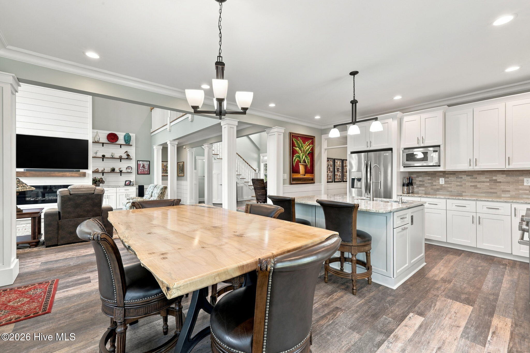 Open kitchen and dining area with white cabinetry, a large island, and a live-edge wood table.