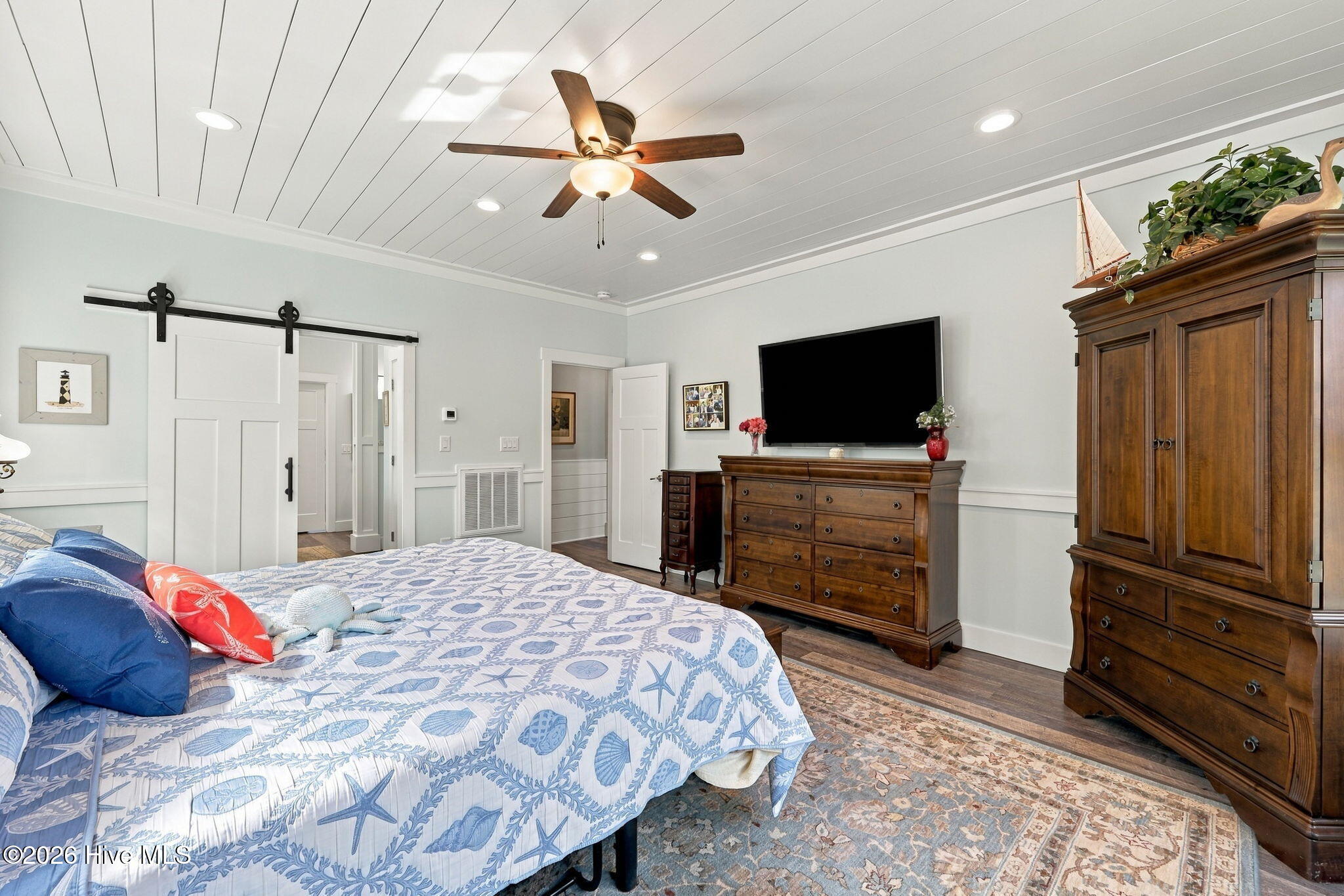 Bedroom with sea-life bedding, a white sliding barn door, and dark wood furnishings.
