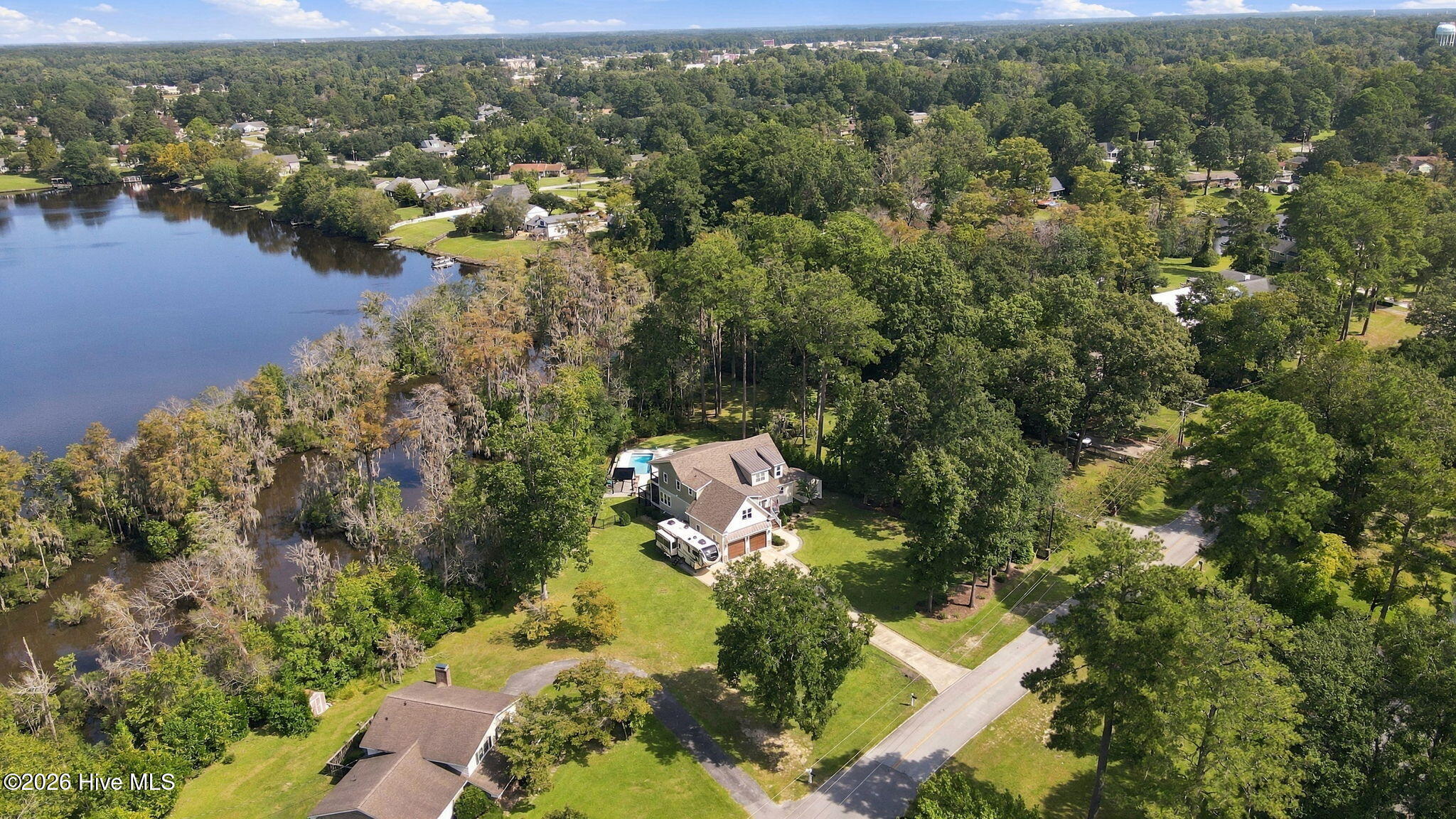 Two-story home with a backyard pool beside a wooded creek.