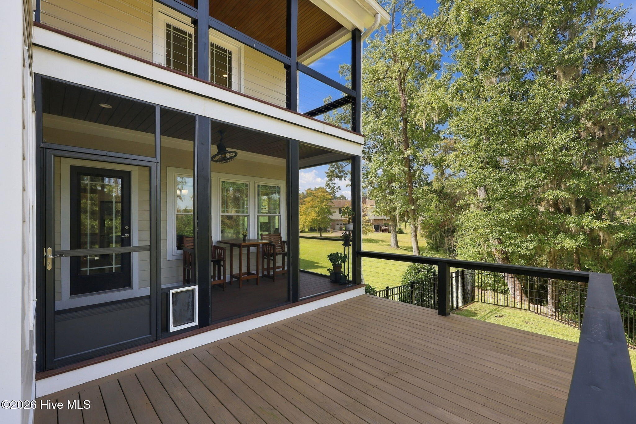 Elevated deck beside a screened porch, overlooking a leafy yard.