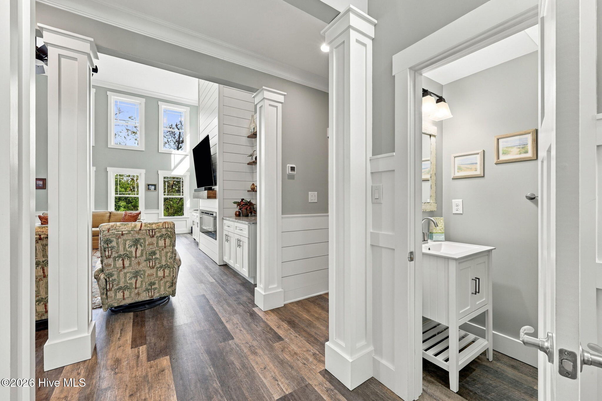 Living room with tall windows, built-in entertainment center, and an adjoining bathroom with white vanity.