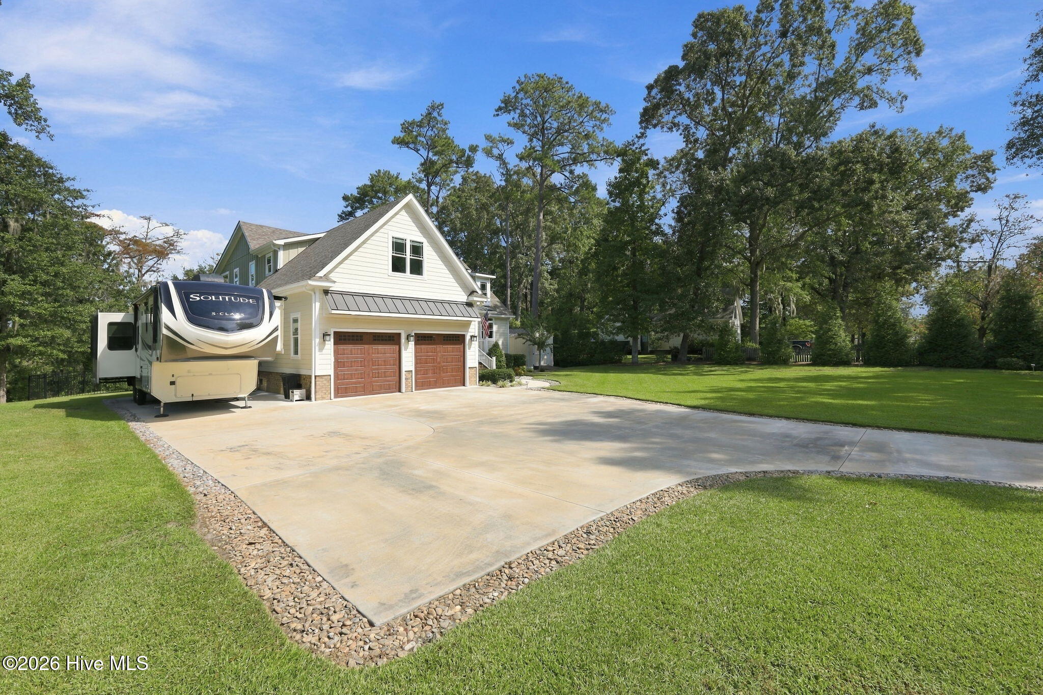 Two-story home with twin garage doors, a broad driveway, and a fifth-wheel RV parked beside it.