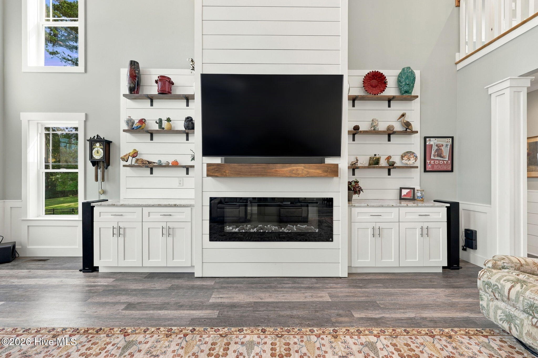 Living room with a television above a linear fireplace and built-in shelving.