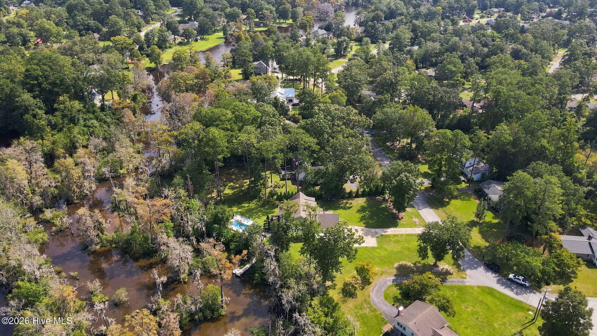 Aerial view of homes and tree-lined streets beside a winding creek.