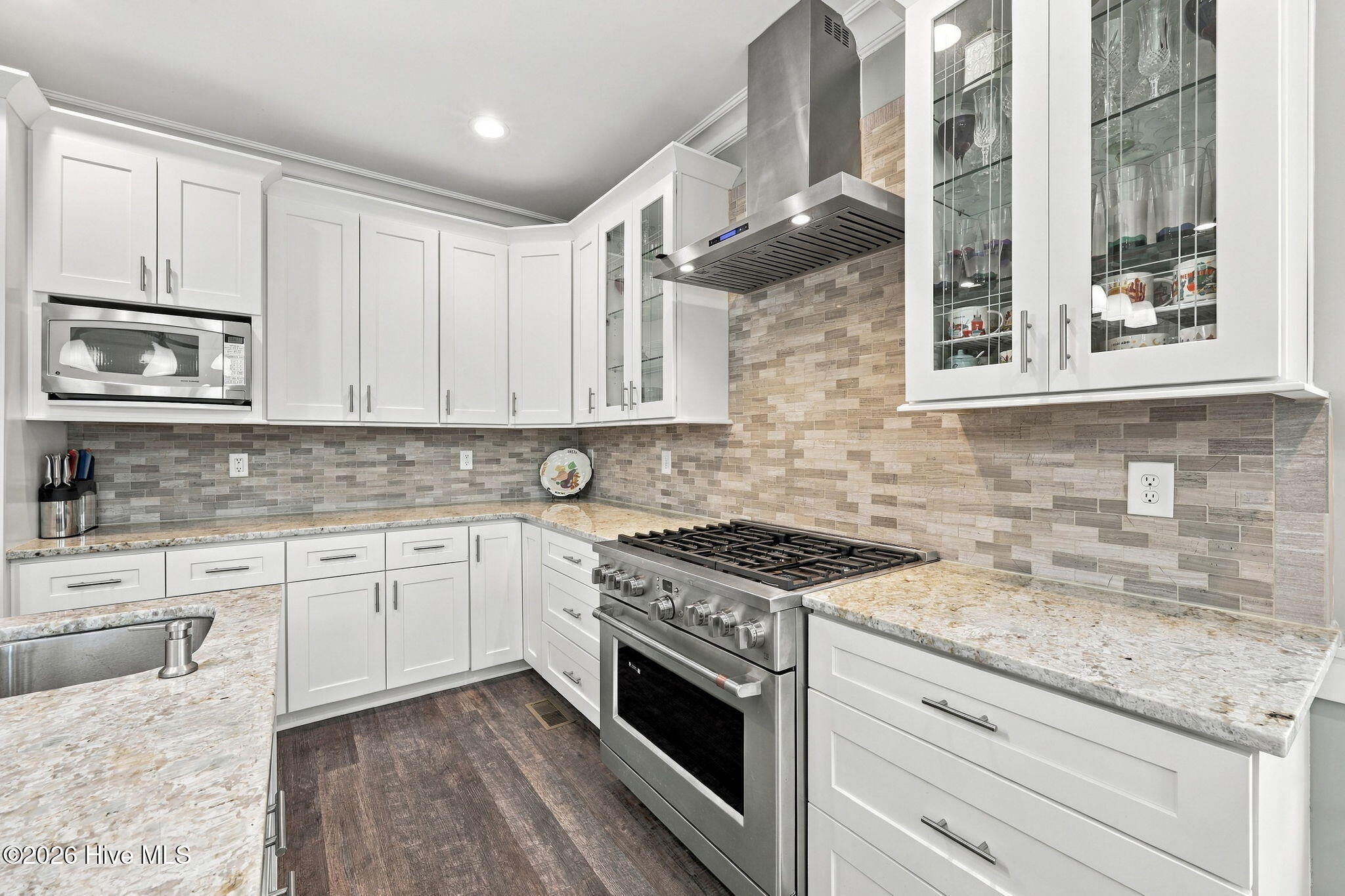 Kitchen with white cabinets, stone counters, gray tile backsplash, and a stainless-steel gas range.