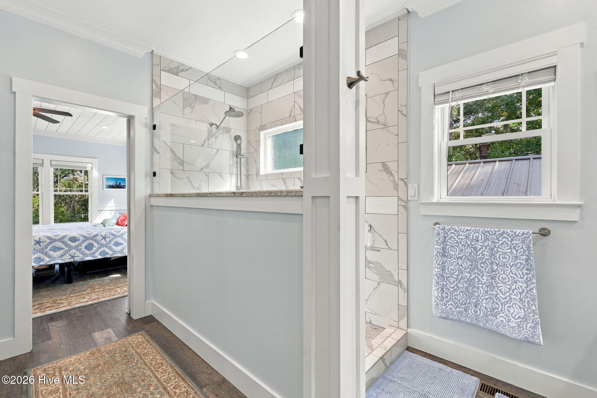 Bathroom with a marble-tiled walk-in shower and bedroom visible through the doorway.