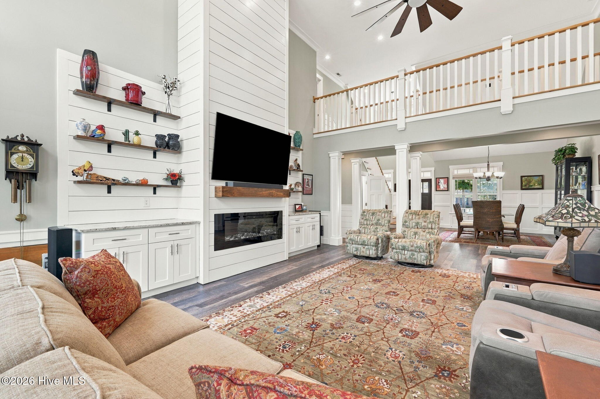 Living room with a tall ceiling, built-in shelving, fireplace, and open dining area.