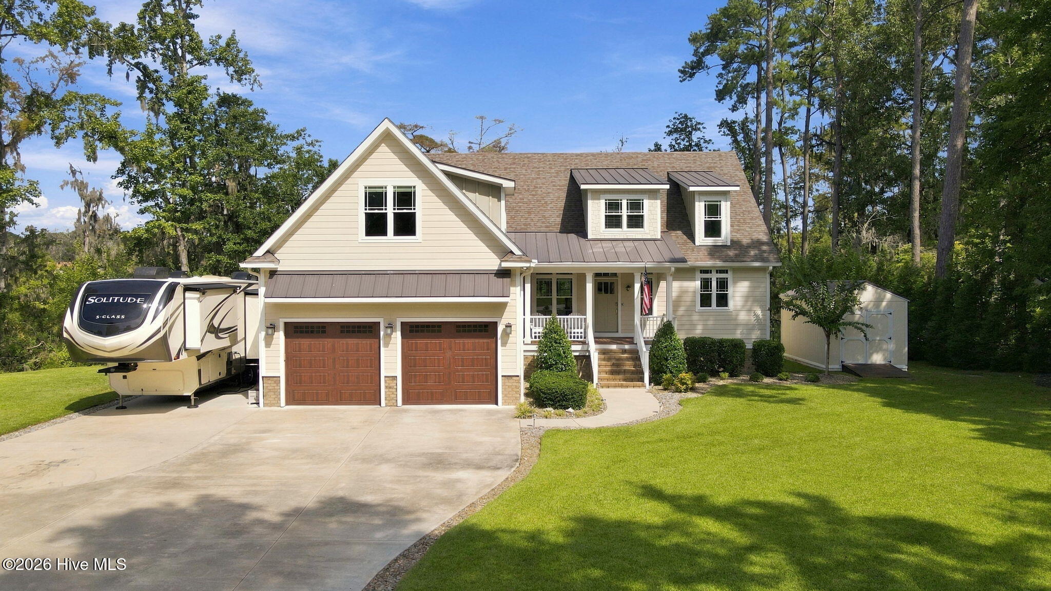 Two-story home with a covered porch, two-car garage, and fifth-wheel RV in the driveway.