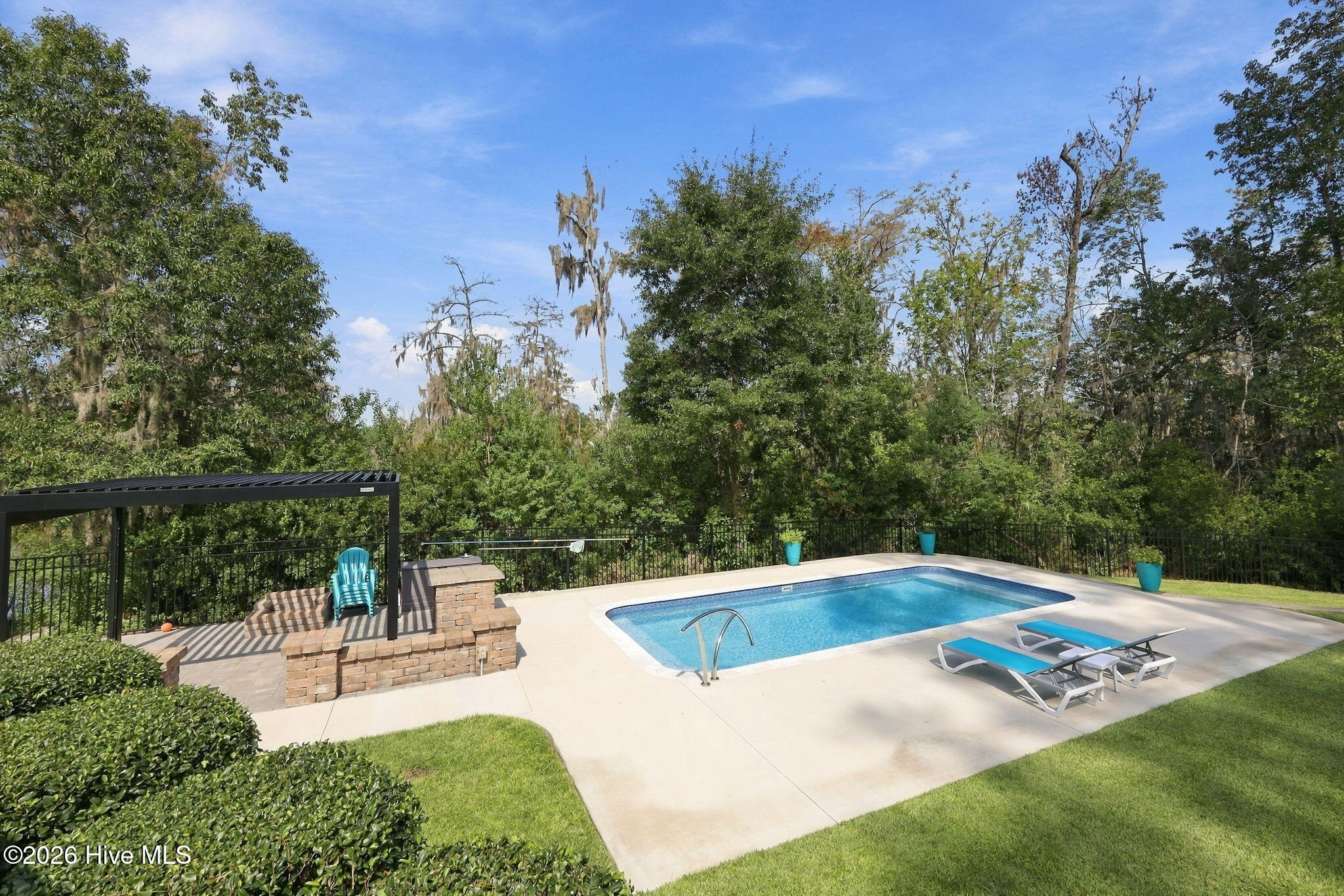Backyard swimming pool with a pergola, brick seating area, and lounge chairs