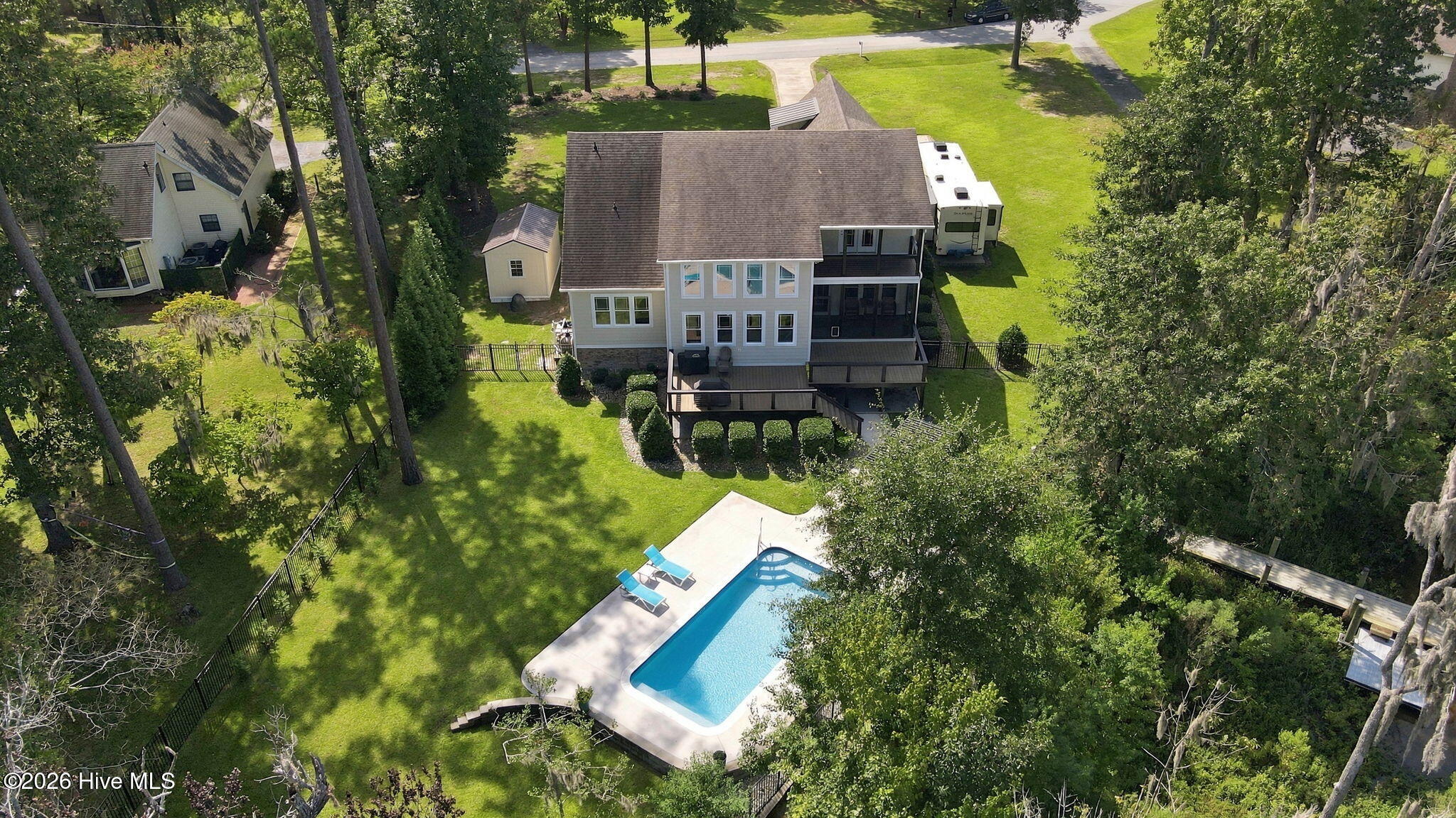 Aerial view of a two-story home with a fenced yard, deck, and swimming pool.