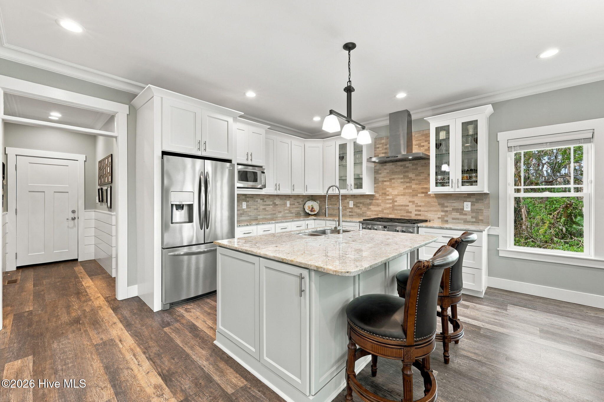 Kitchen with white cabinetry, stainless steel appliances, and a large island with bar seating.