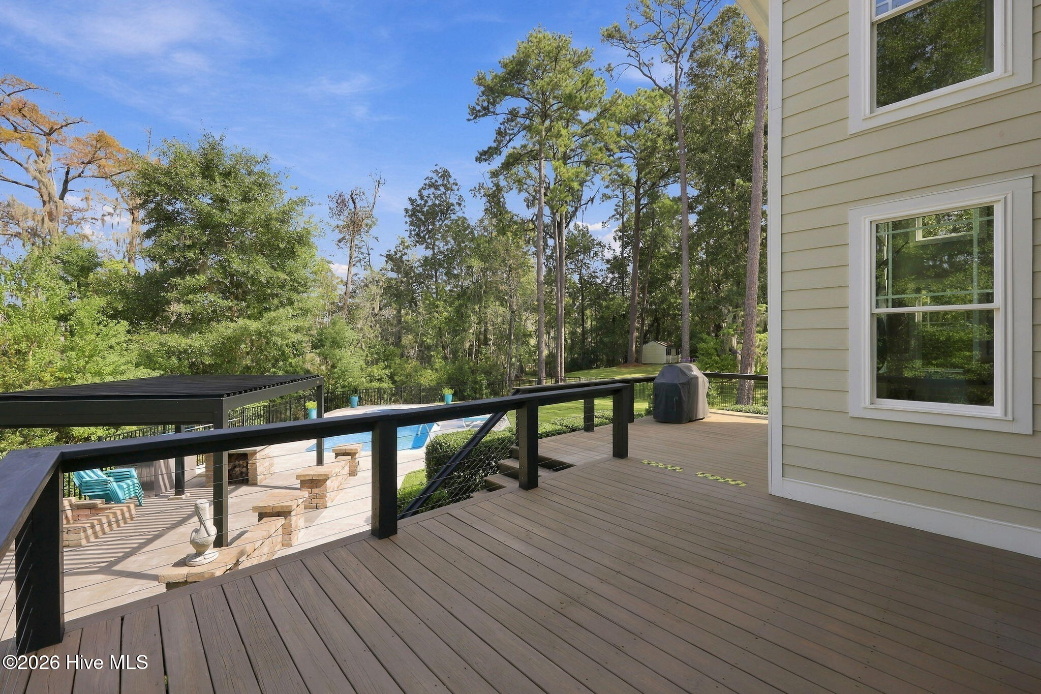 Deck overlooking a swimming pool, patio seating, and a wooded yard.