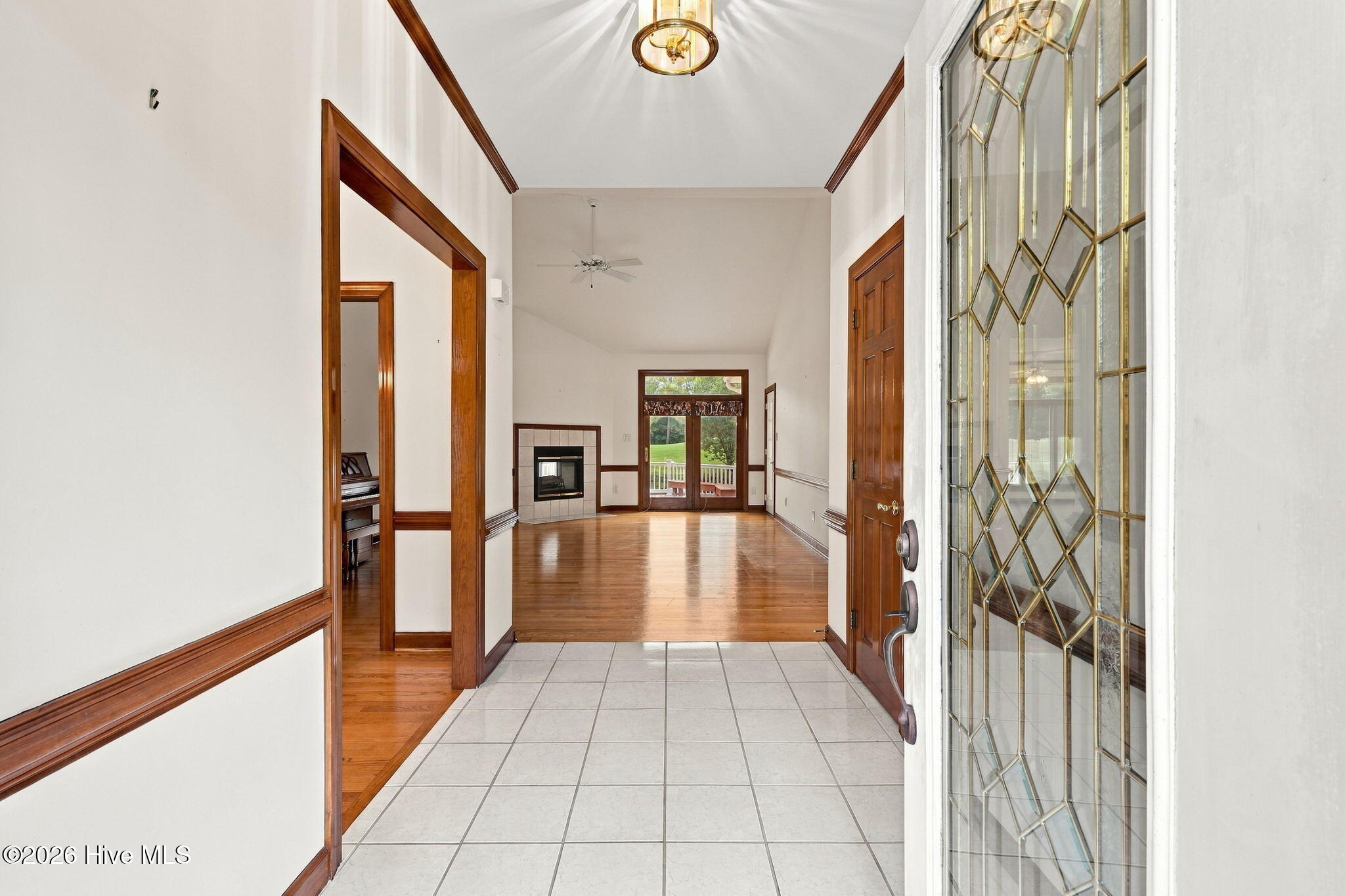 Tiled entryway opens to a hardwood living room with a fireplace and decorative glass front door.