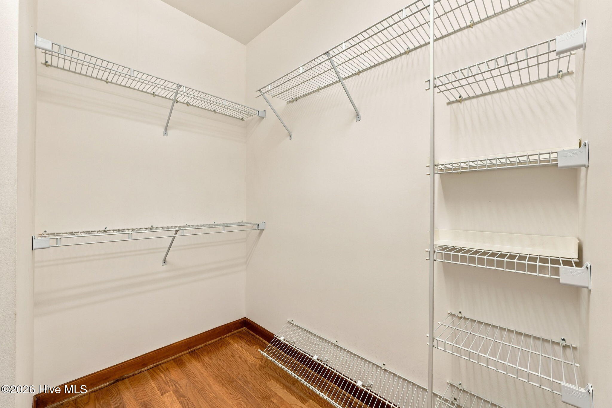 Walk-in closet with extensive wire shelving and a hardwood floor.