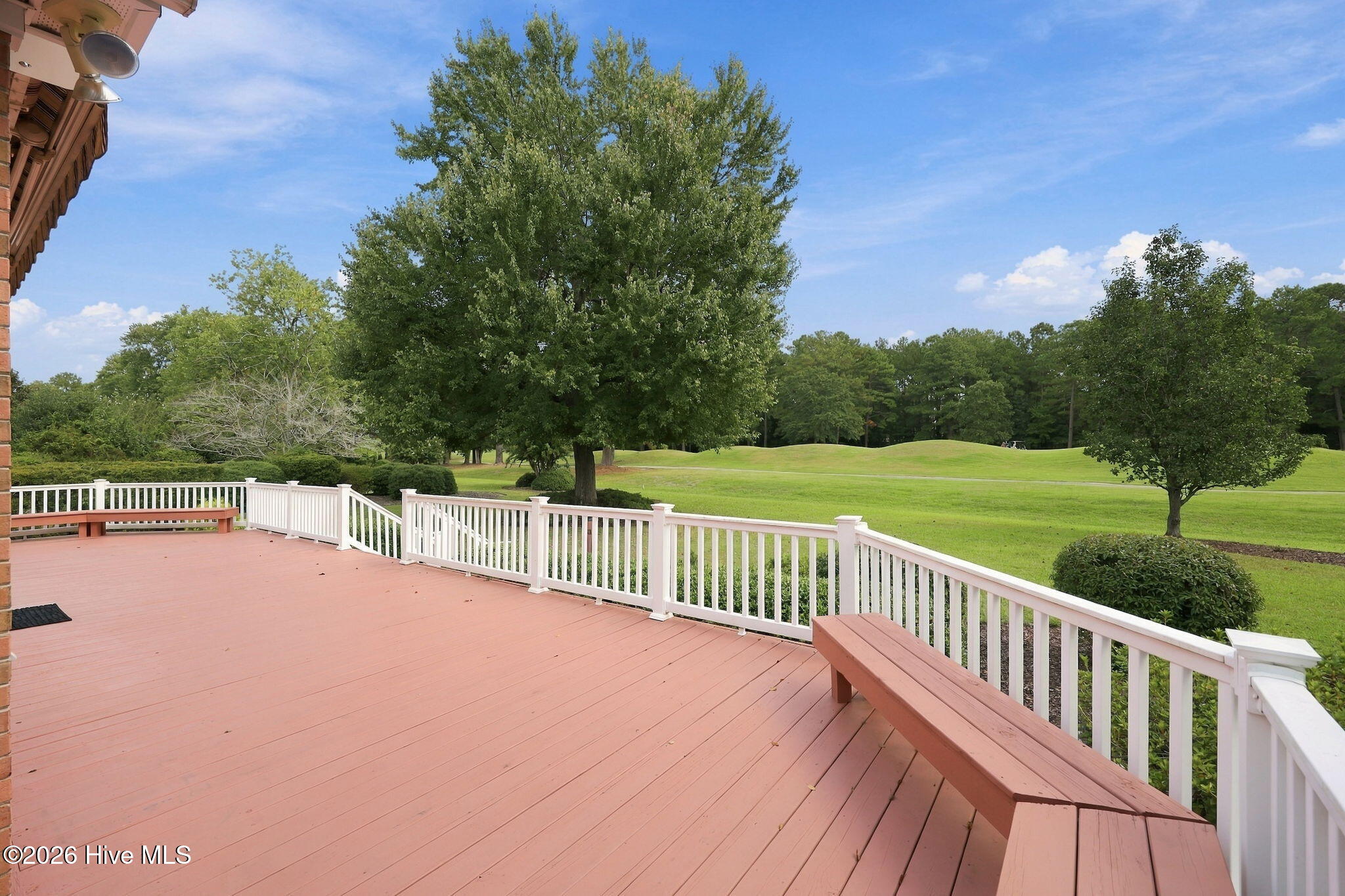 Deck with white railings and built-in benches overlooking a green golf course.