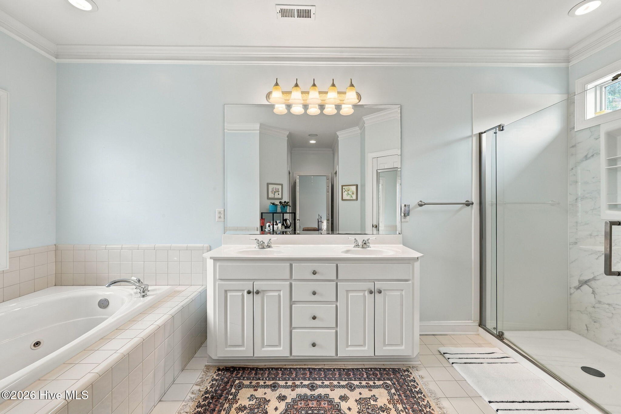 Primary bathroom with a double-sink vanity, soaking tub, and glass-enclosed shower.