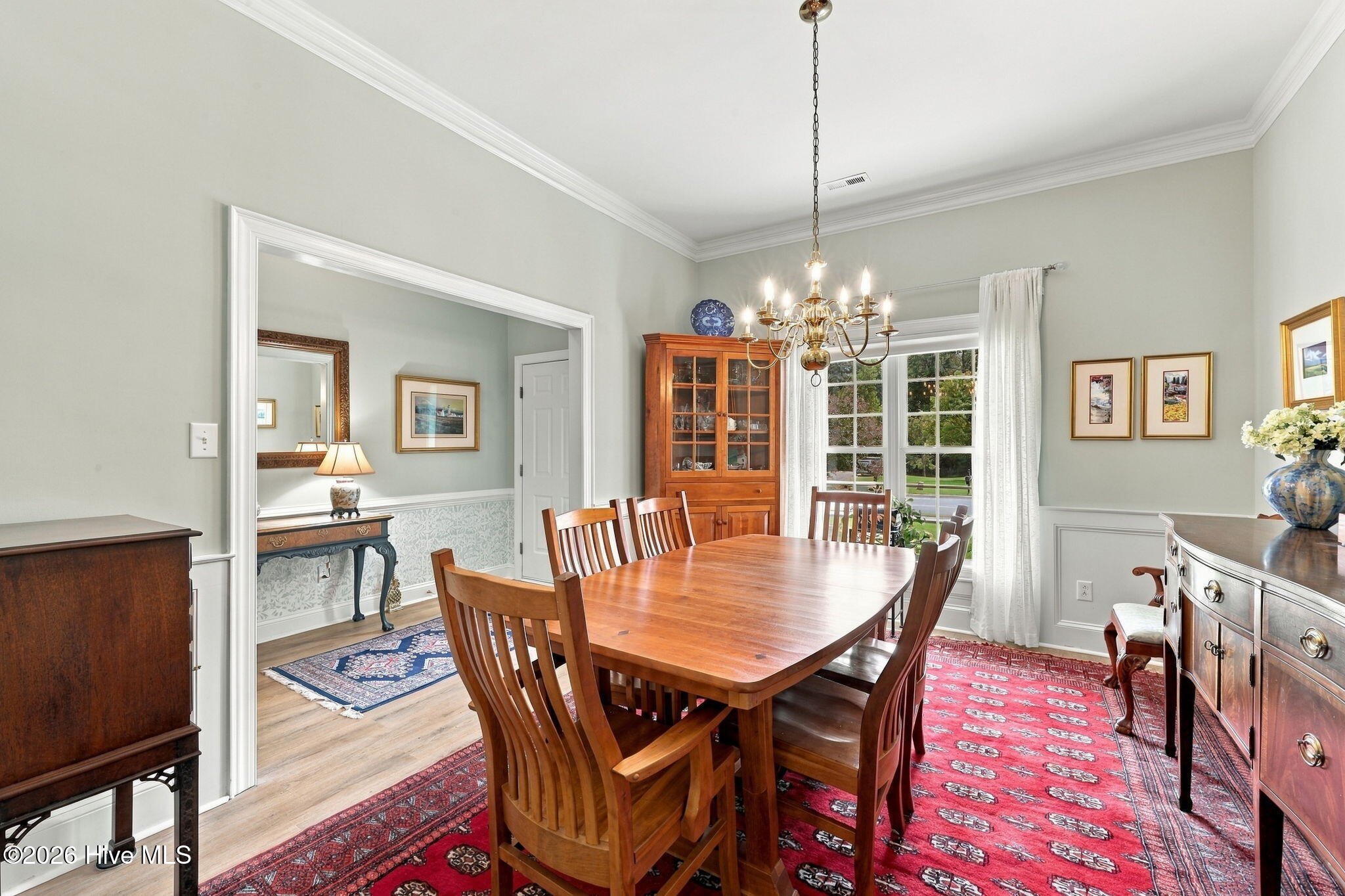 Dining room with a wooden table, glass-front china cabinet, and red patterned rug.