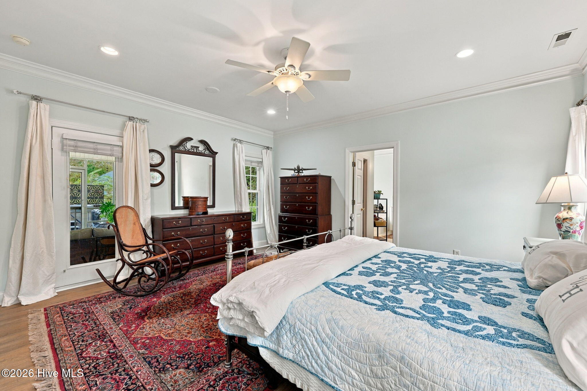 Bedroom with a blue-and-white quilted bed, dark wood dressers, and a wooden rocking chair.