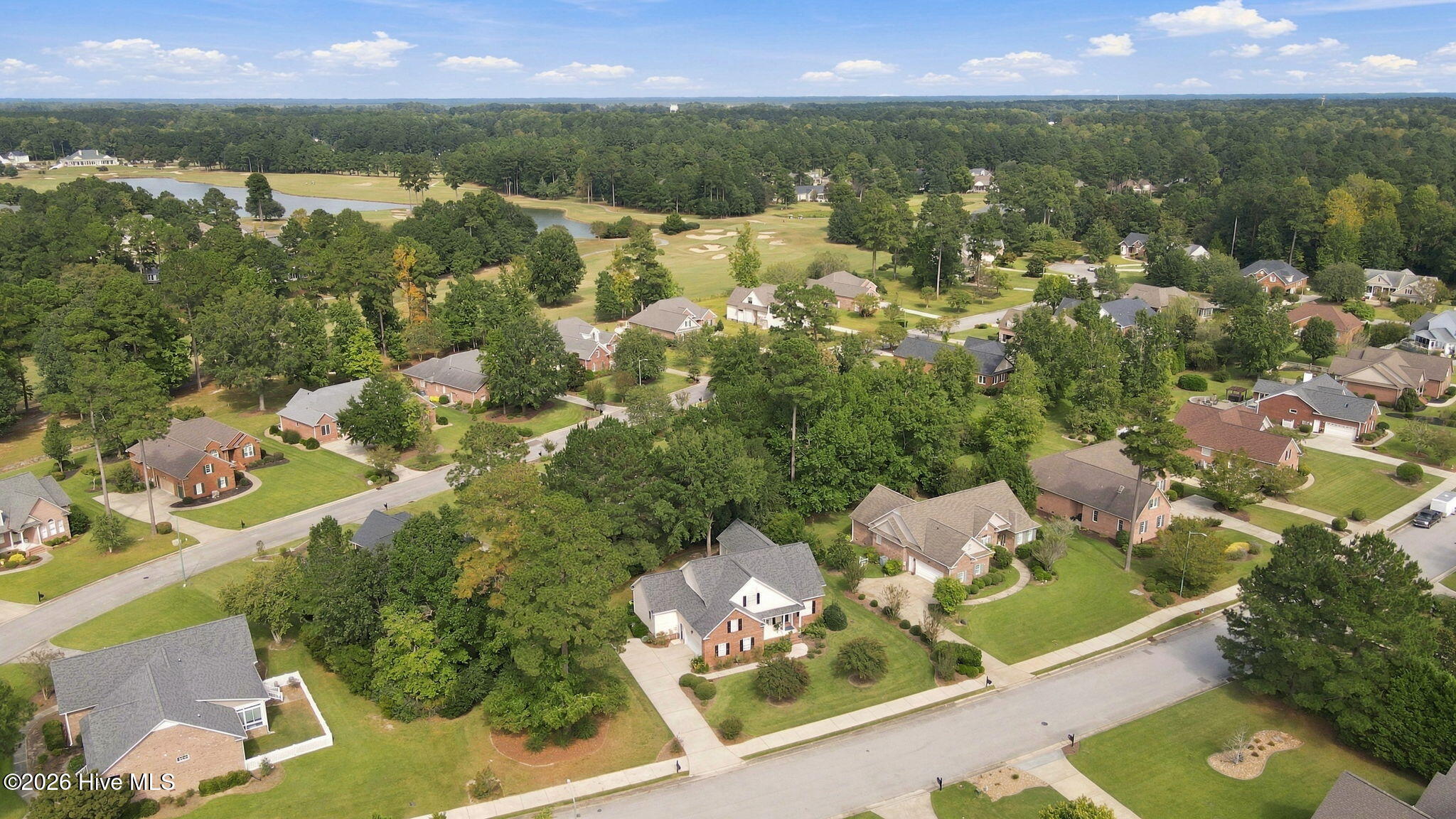 Aerial view of a residential neighborhood beside a golf course, with ponds and tree-lined streets.