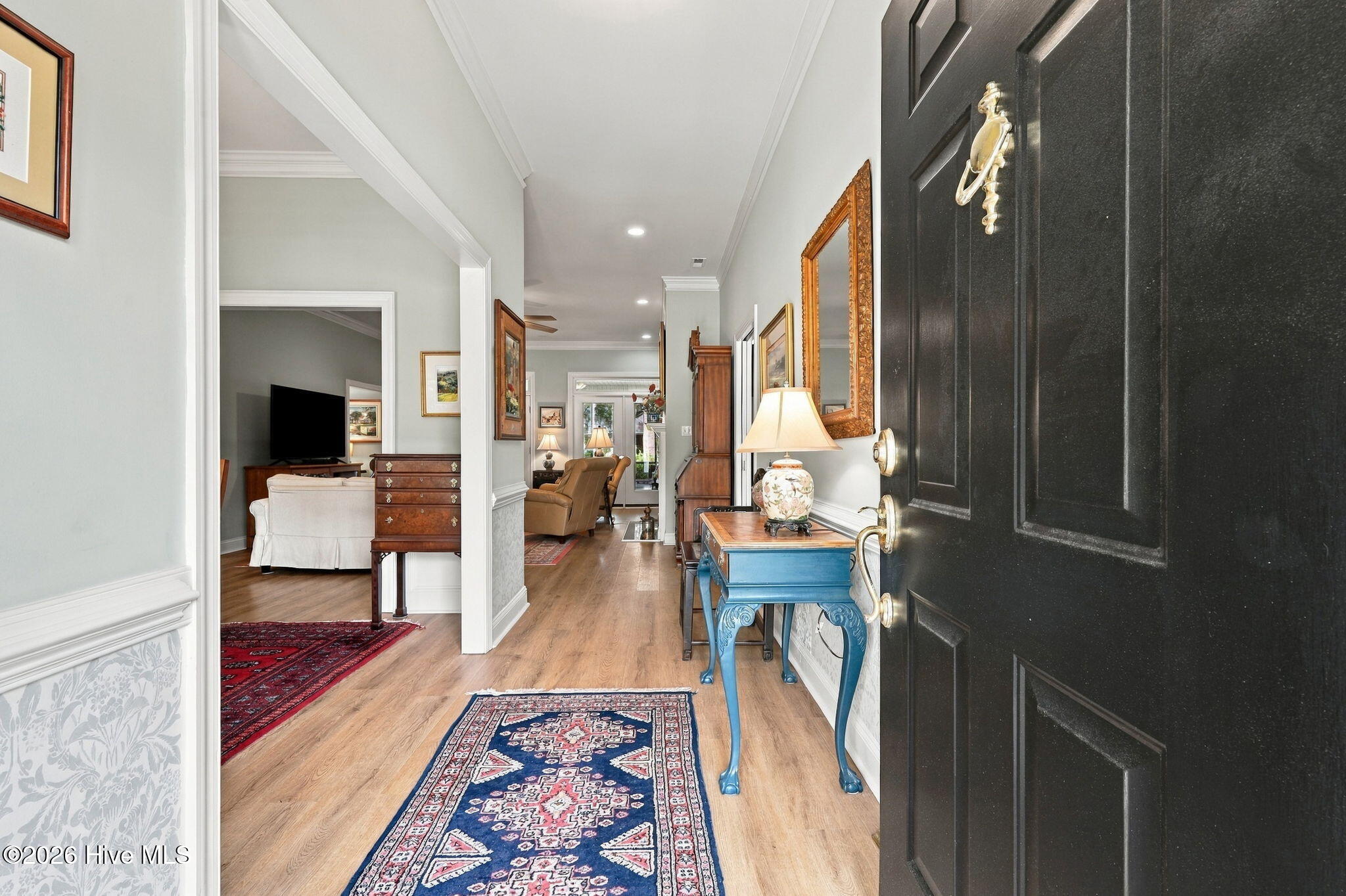 Furnished entryway with a blue console table, patterned rugs, and adjoining living areas.