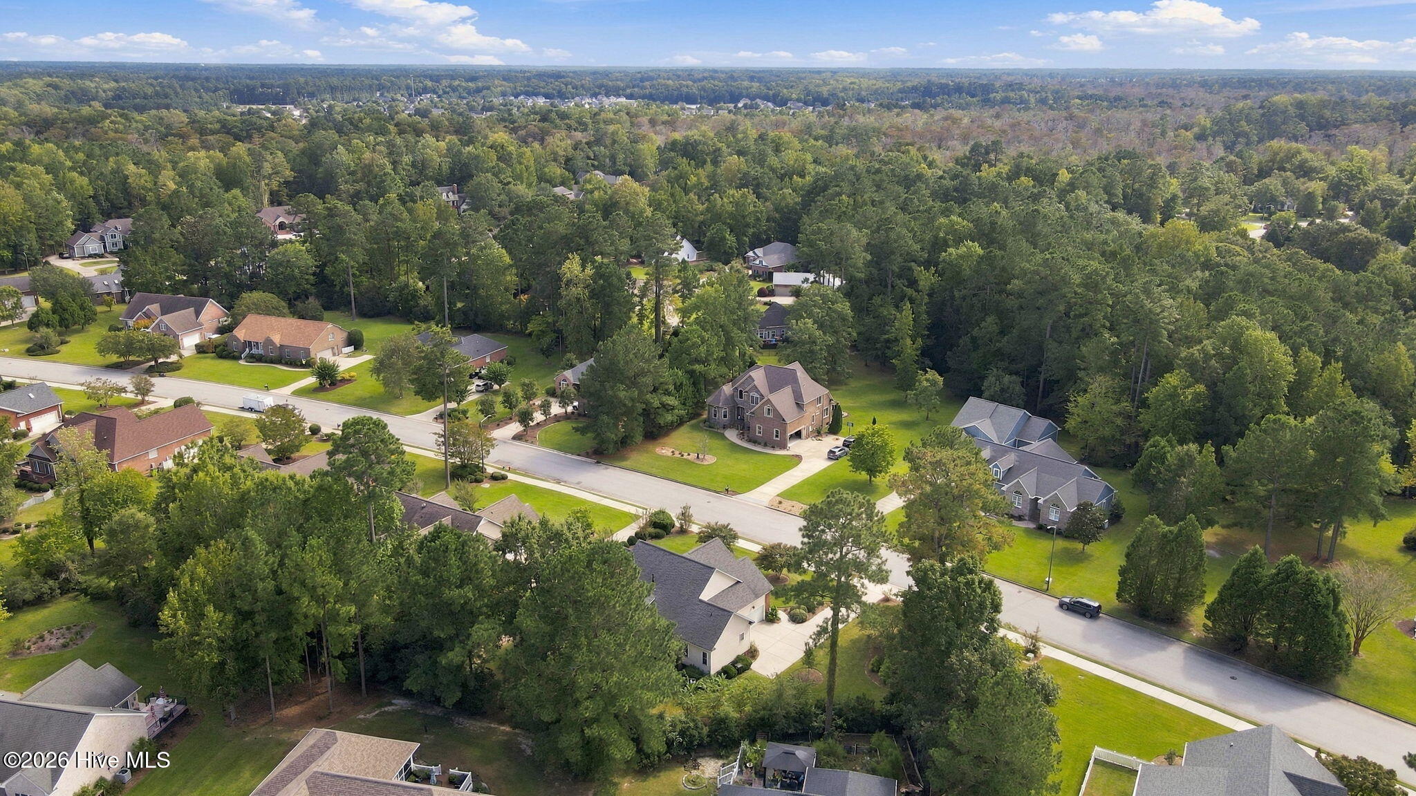 Aerial view of a leafy residential neighborhood with detached homes and winding streets.
