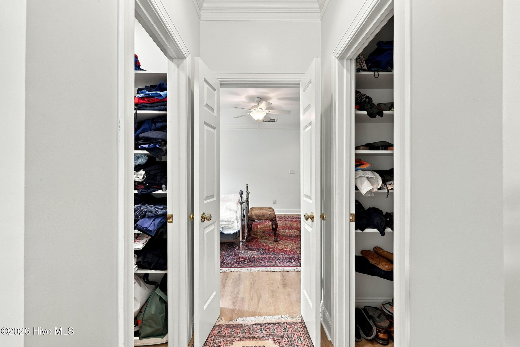 Hallway with open closets on both sides and a bedroom at the end.