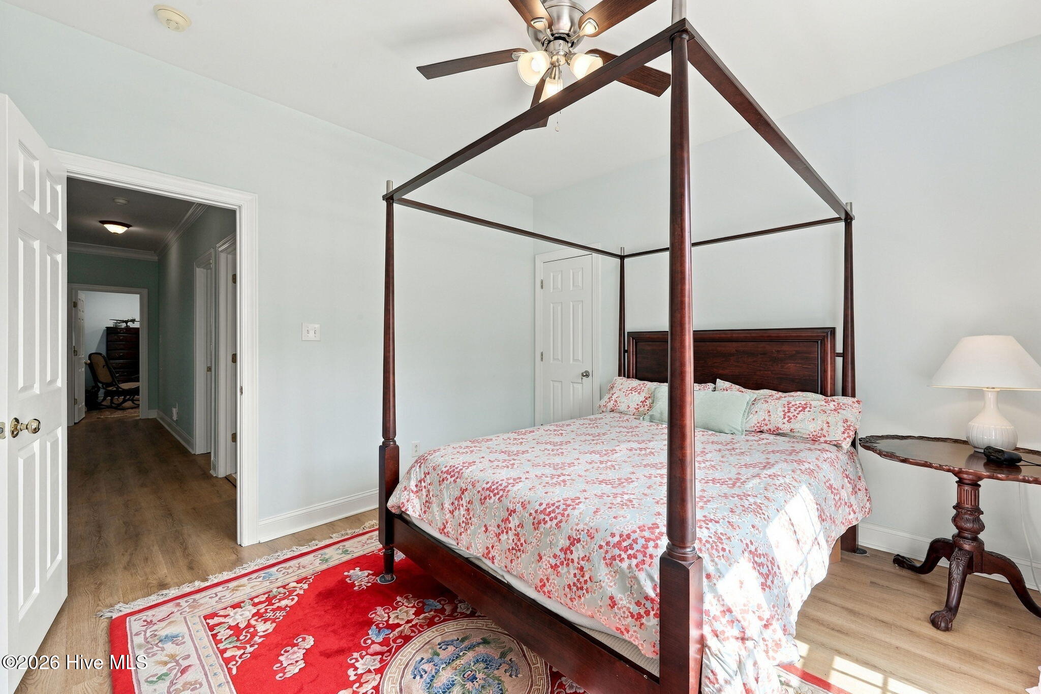 Bedroom with a dark wood four-poster bed, floral bedding, and a red patterned rug.