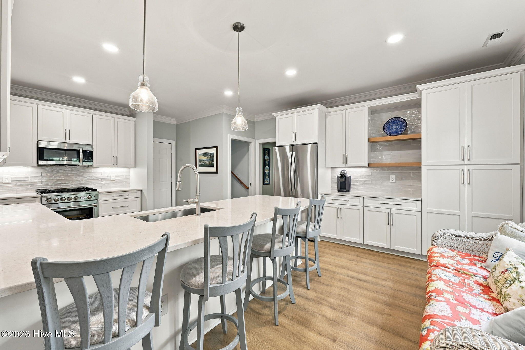 Kitchen with white cabinets, stainless steel appliances, and a large island with gray bar stools.