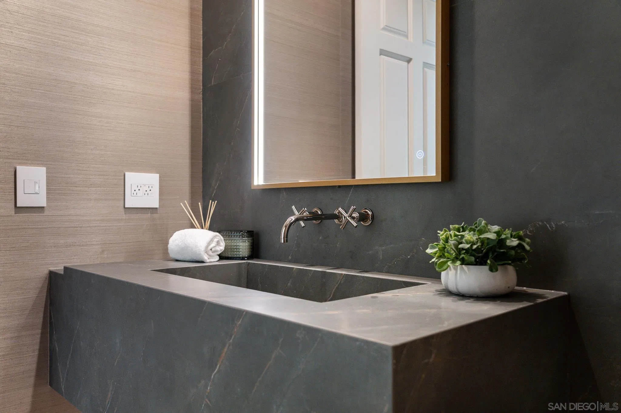 Modern bathroom vanity with an integrated dark stone basin and wall-mounted faucet.
