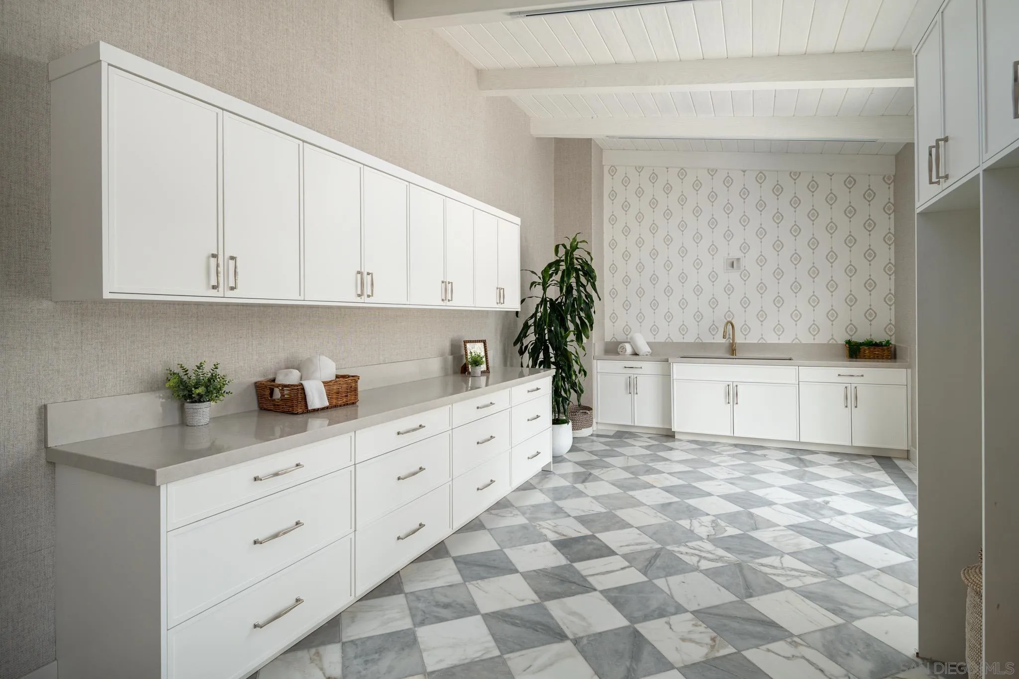 Laundry room with white cabinetry, a sink, patterned backsplash, and gray-and-white checkerboard flooring.