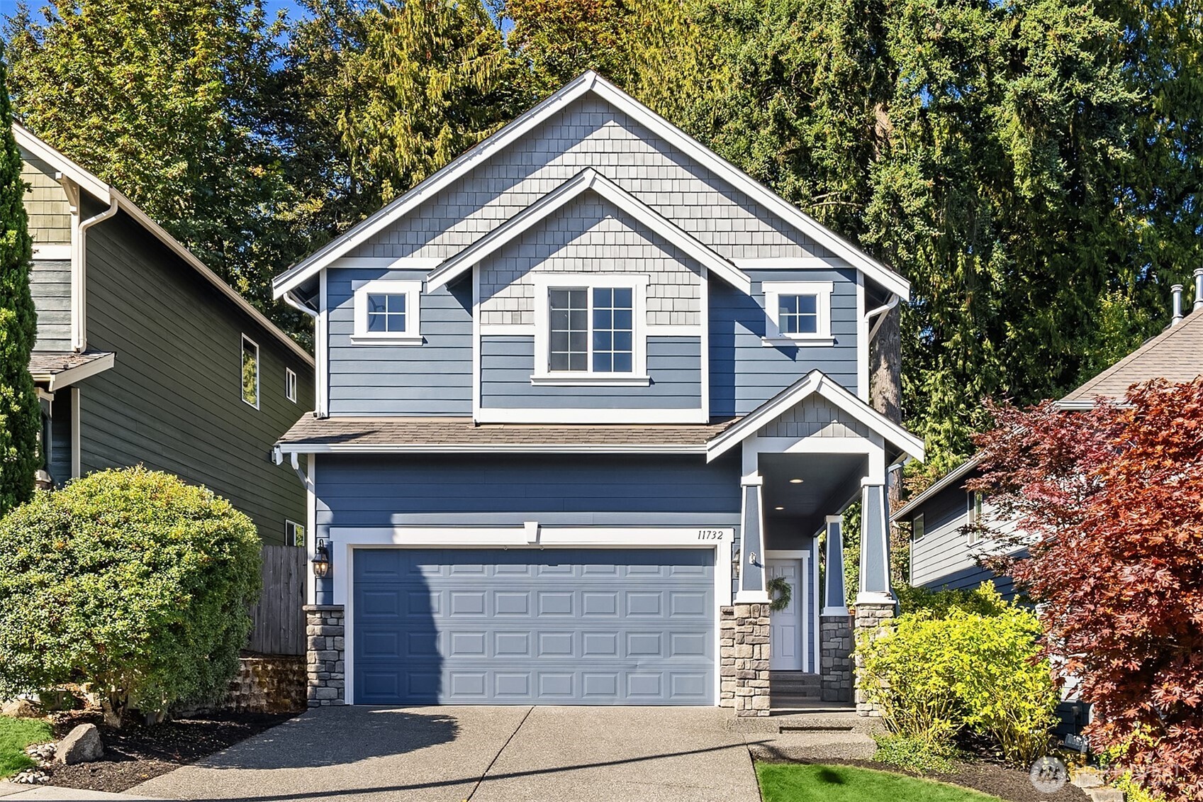 Blue two-story house with white trim, a double garage, and a covered front entry.