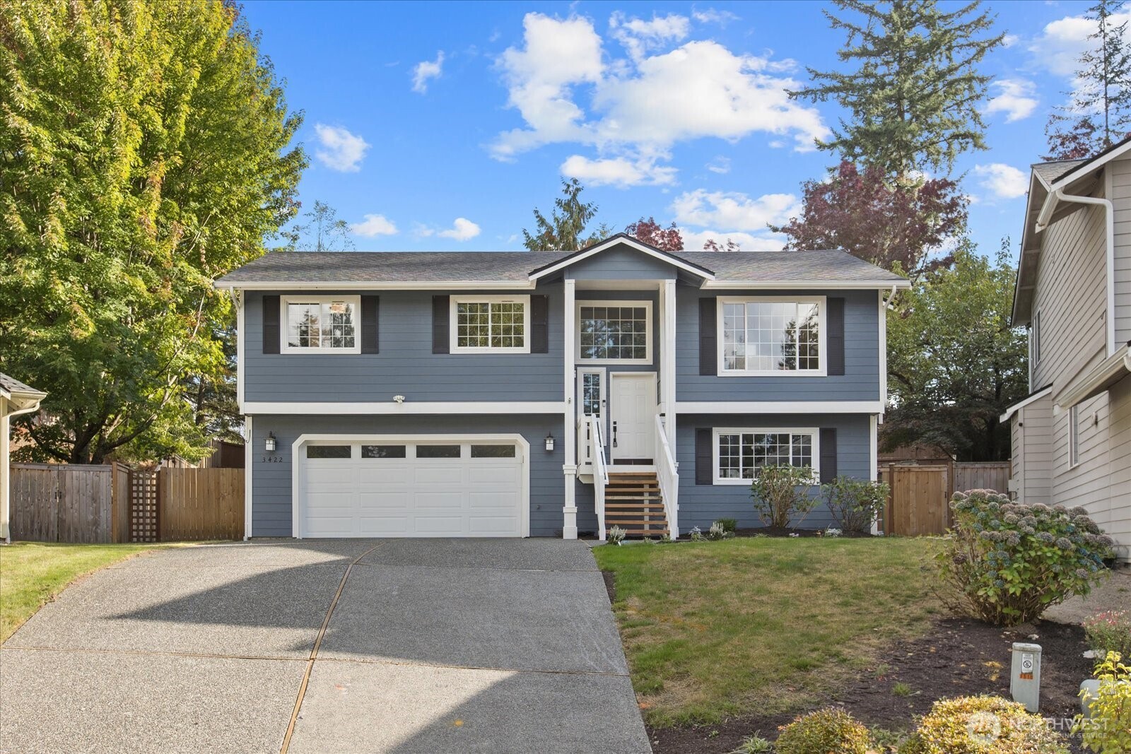 Blue split-level house with white trim, a double garage, and central entry stairs.