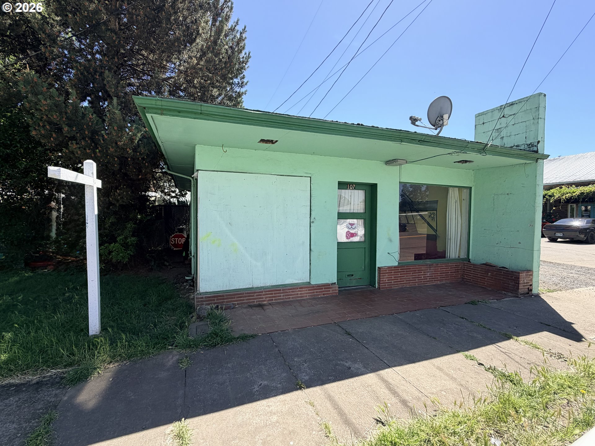Mint-green storefront at 107, with a brick base and a covered window.