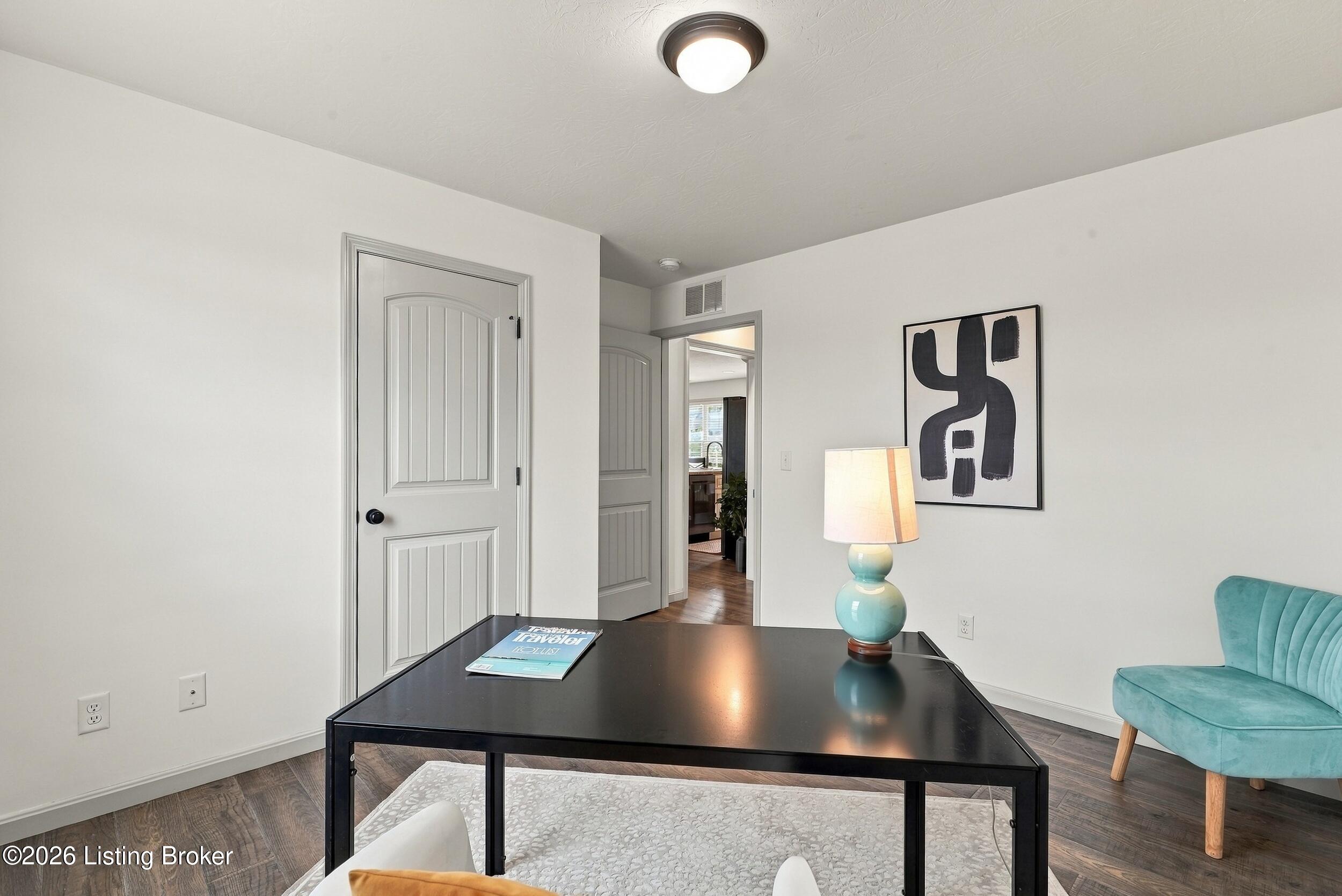 Home office with a black desk, turquoise chair, and framed abstract artwork.