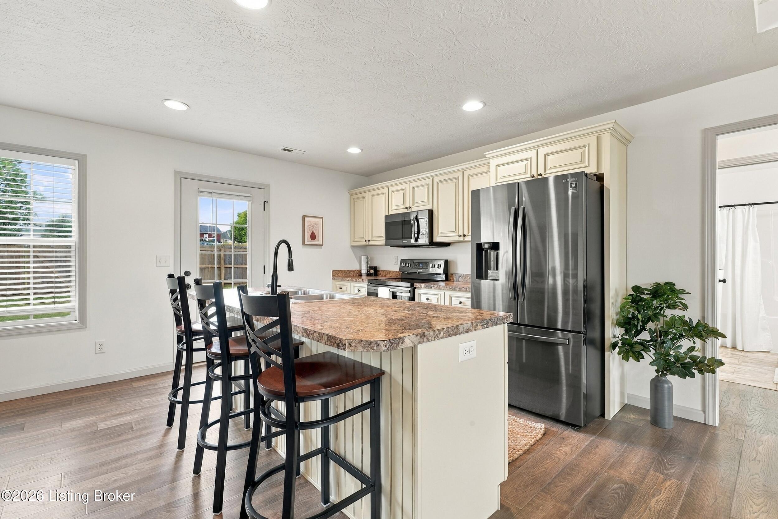 Kitchen with a large island, granite-look counters, cream cabinets, and stainless steel appliances.