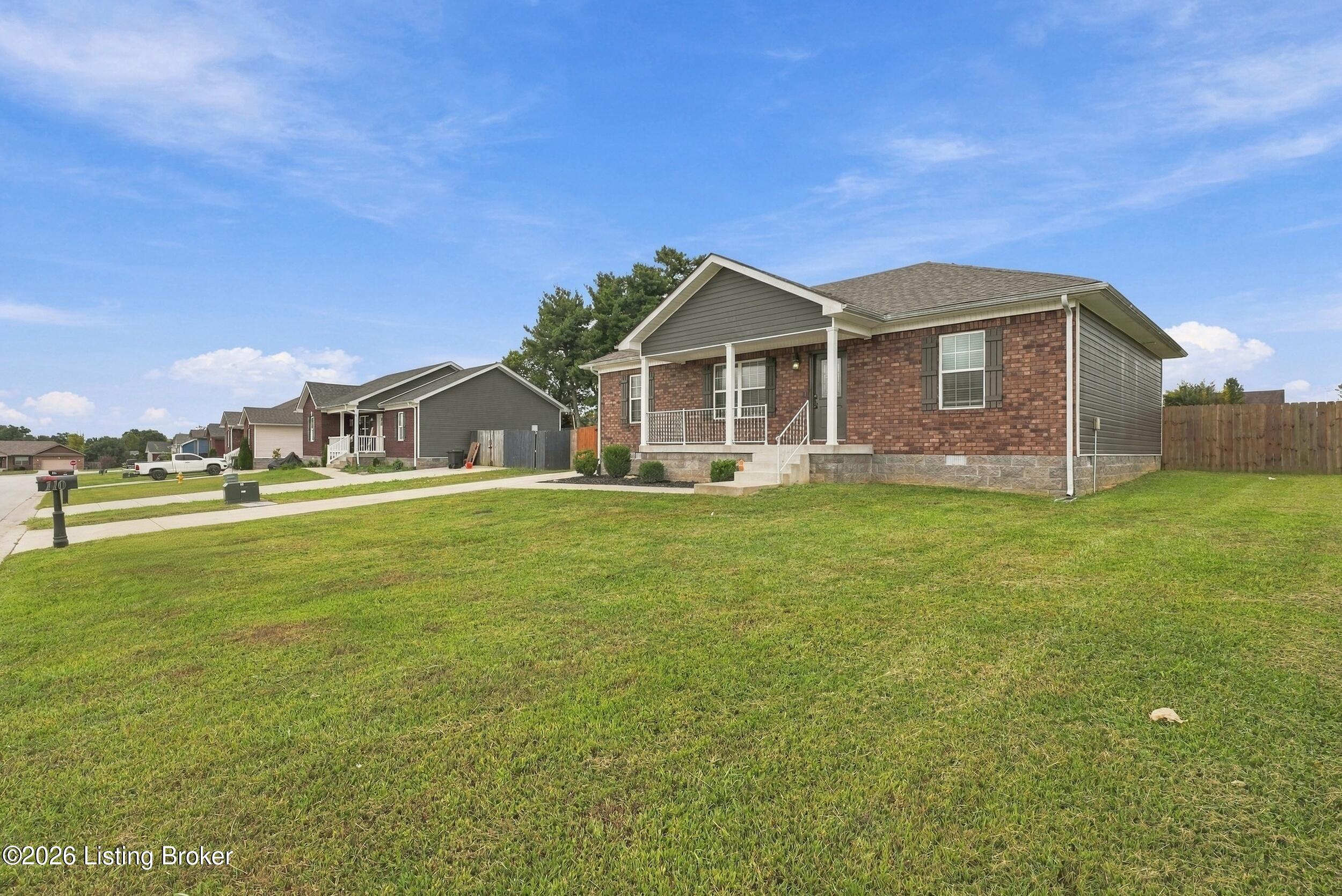 Brick home with a covered porch and broad front lawn on a residential street.
