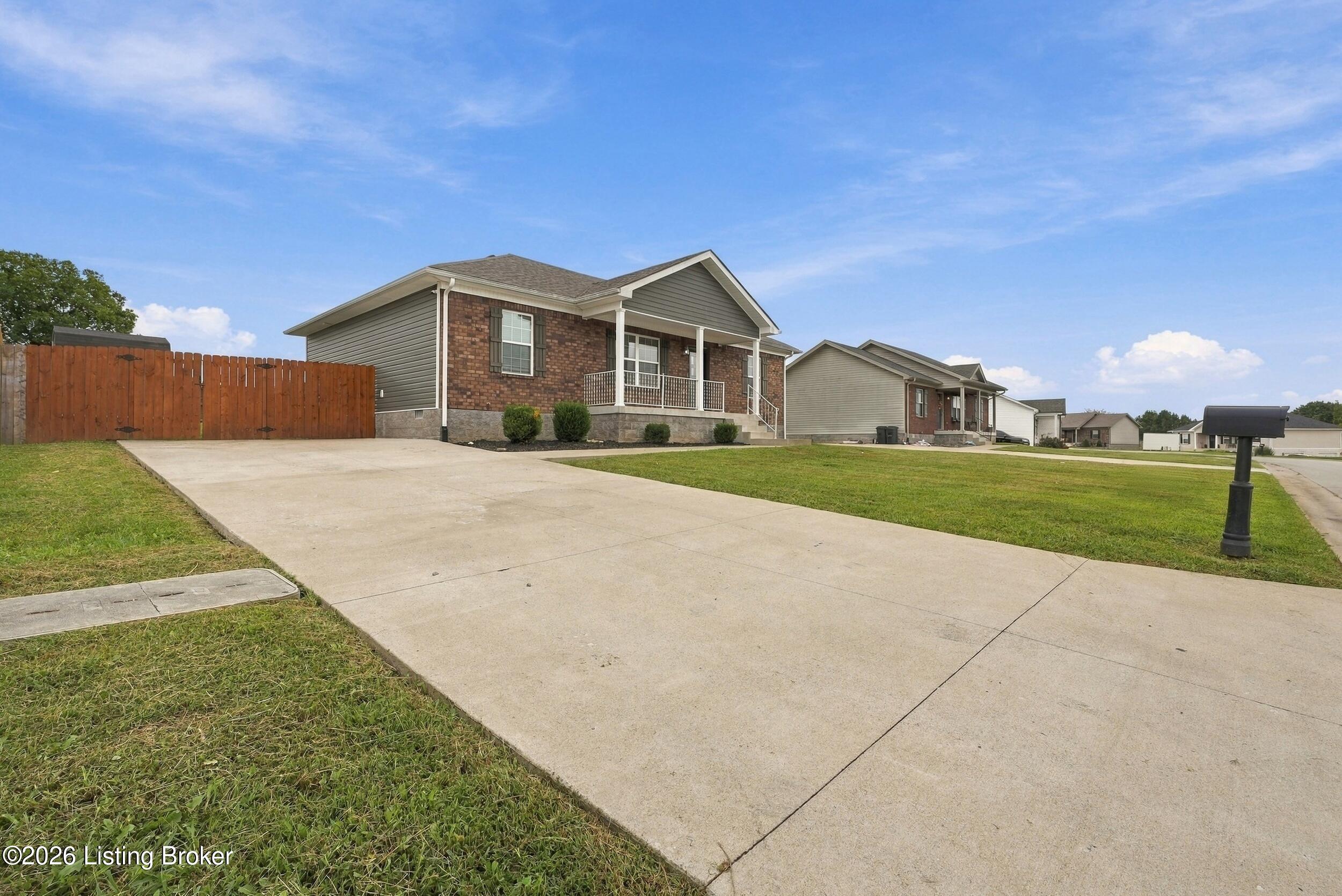 Single-story brick-and-gray home with a wide concrete driveway and wooden privacy fence.