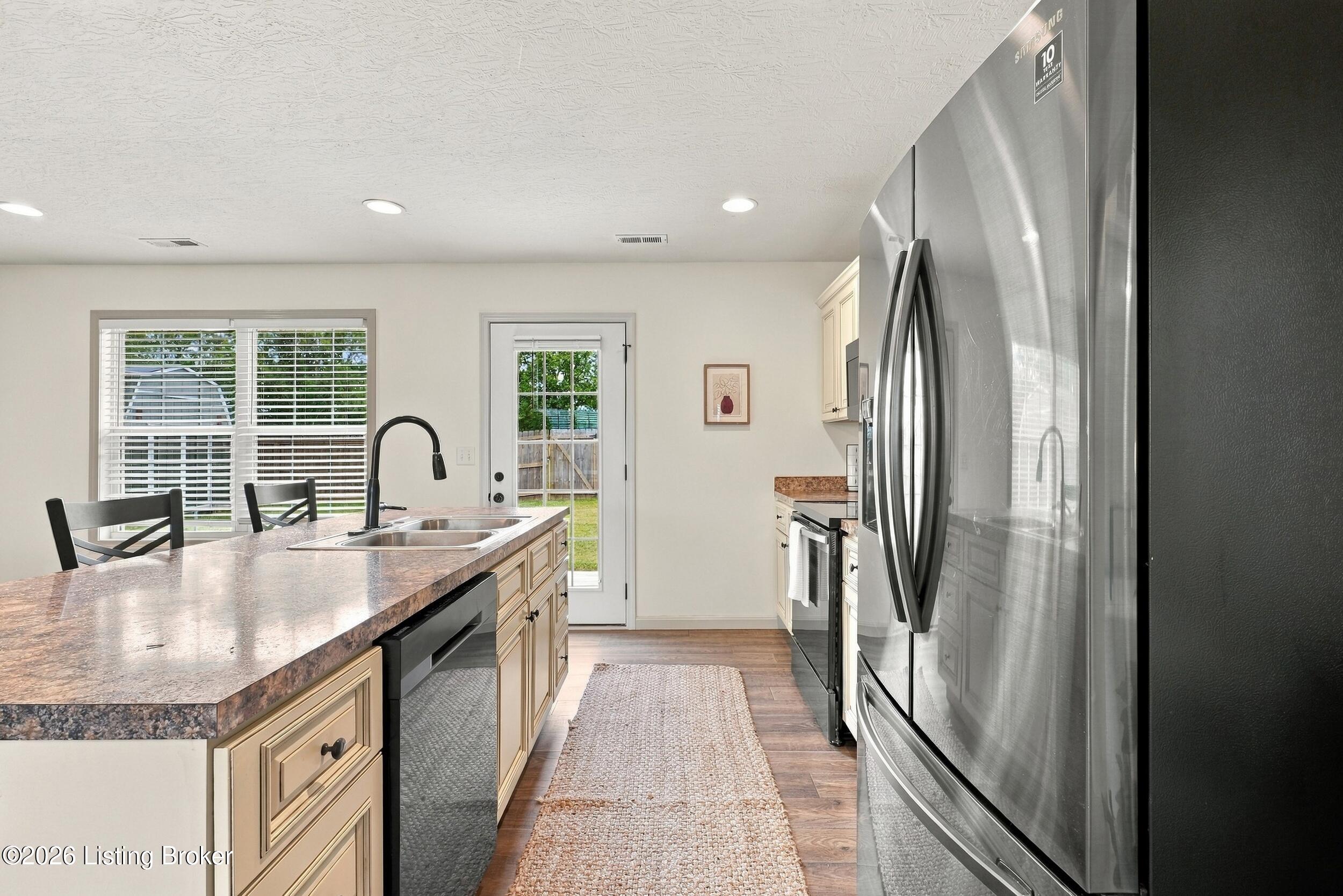 Kitchen with a large stone-look island, stainless steel appliances, and a glass-paneled door to the yard.