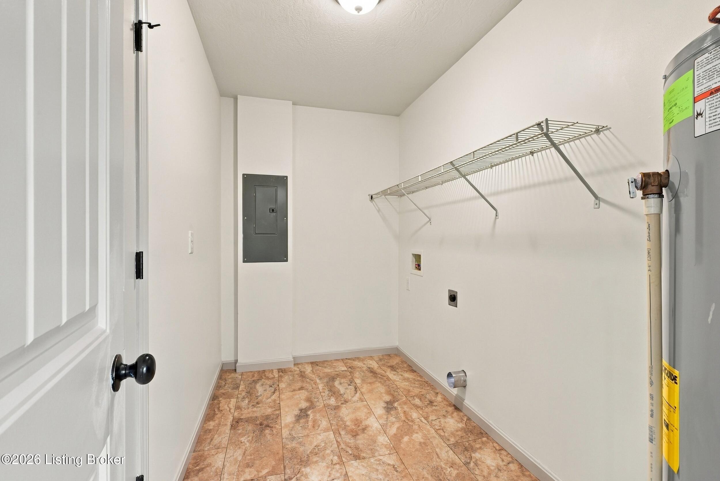Utility room with tan tile flooring, wire shelf, washer hookups, and a water heater.